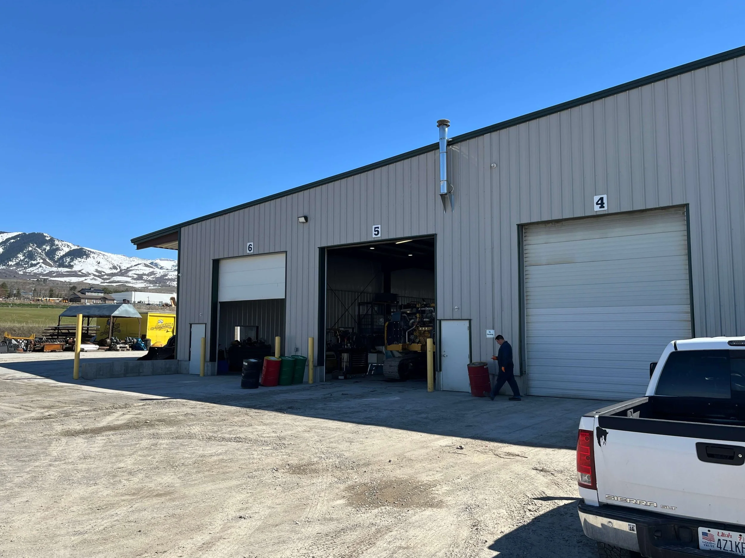 Industrial warehouse with open garage doors and a snowy mountain backdrop