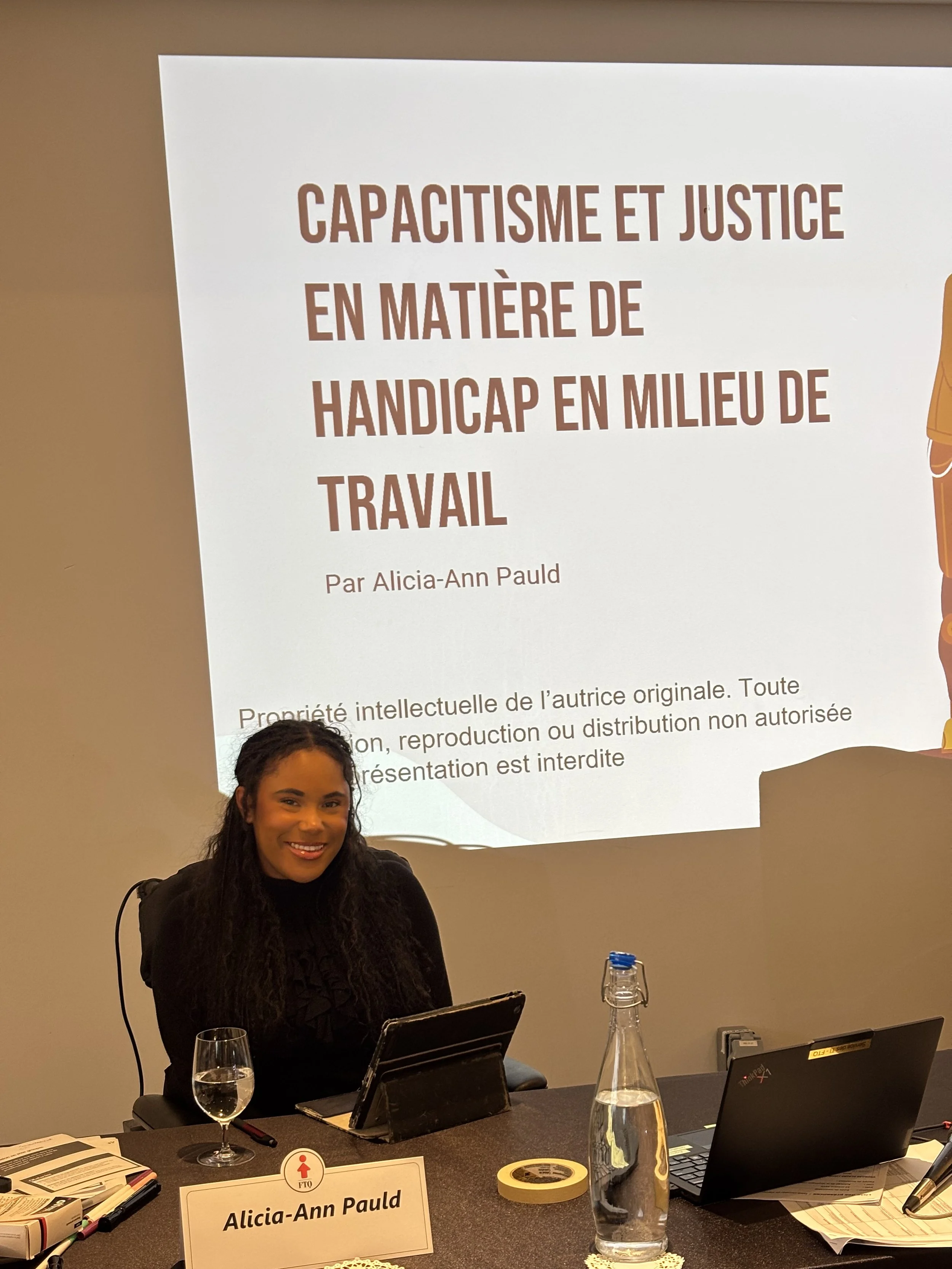 Allie at the FTQ Leadership School, sitting in her motorized wheelhair in front of her powerpoint presentation that reads Ableism and justice in terms of disability in the workplace. October 22nd 2025.