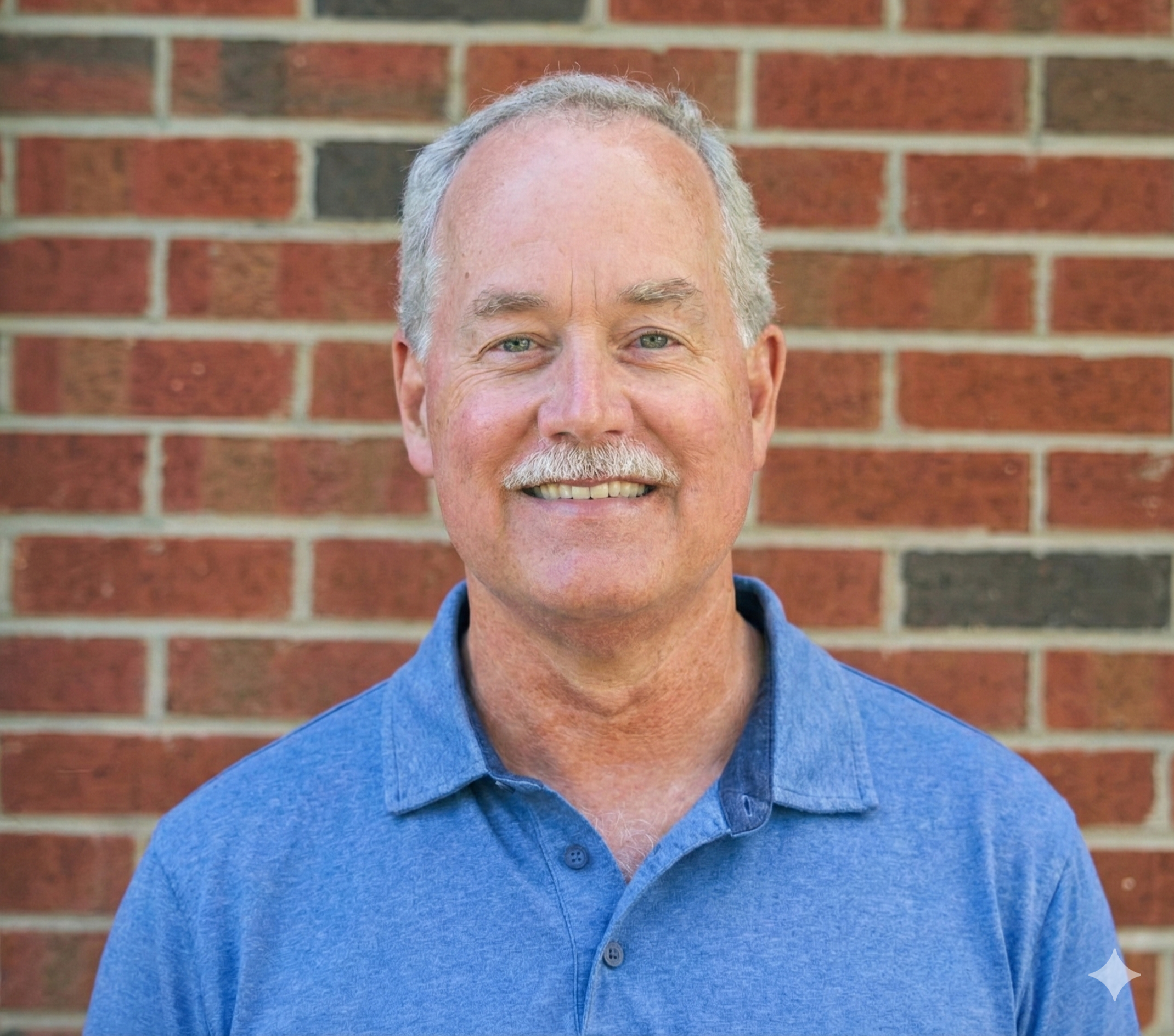 Man smiling in front of a brick wall