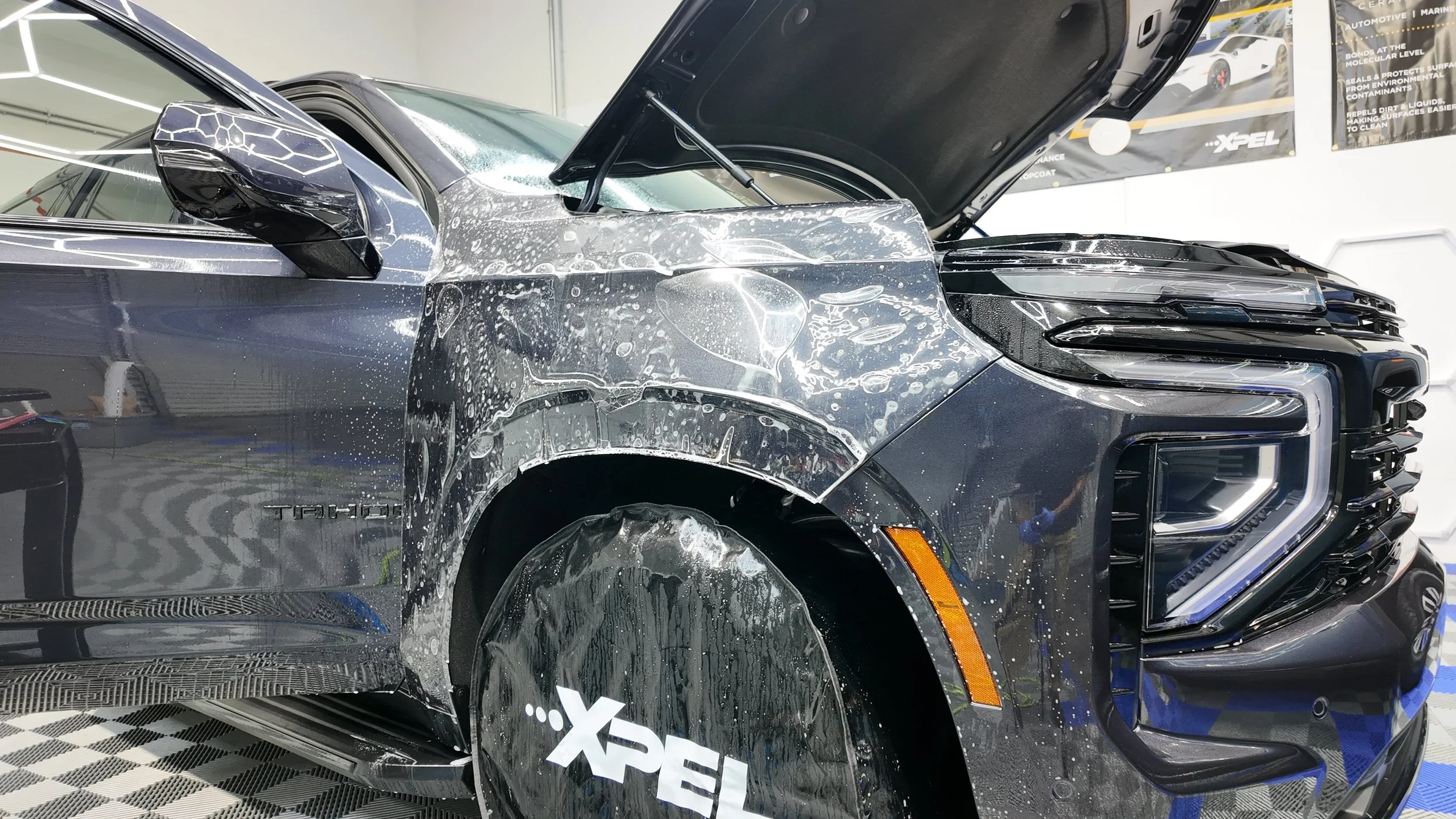 Xpel paint protection film sitting on the fender of a luxury SUV at NextGen Auto Spa.