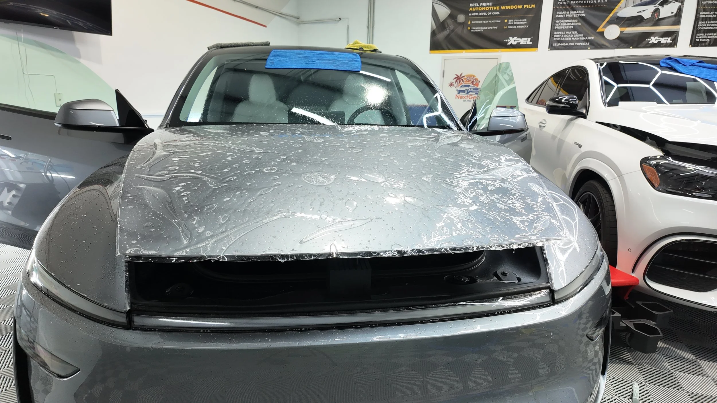 Silver Tesla with Xpel paint protection film on the hood, inside NextGen Auto Spa. 