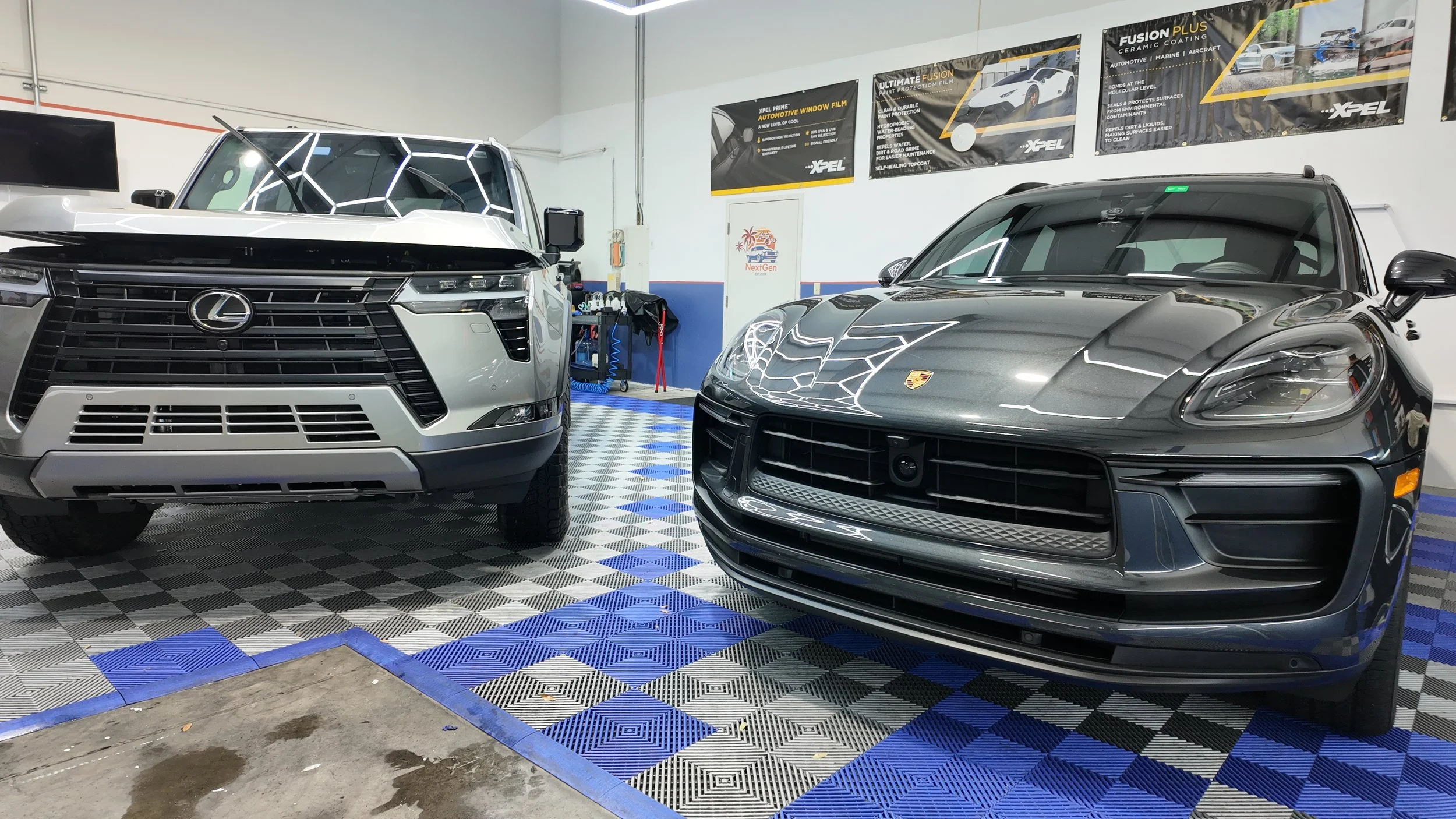 A Lexus SUV and a silver Porsche sports car inside NextGen Auto Spa after paint protection film installation. 