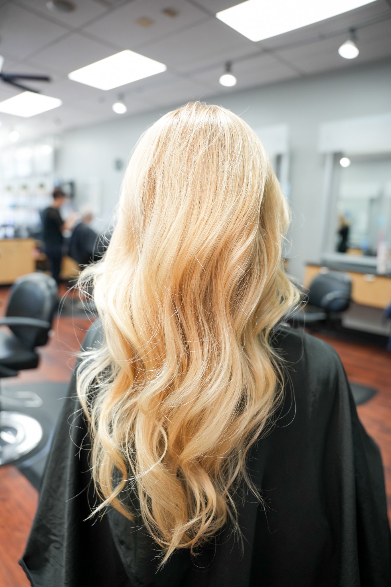 Blonde woman with long wavy hair sitting in a salon chair