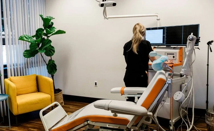 A female technician preparing a TMS therapy chair for Henderson post-traumatic stress disorder psychiatric treatment.