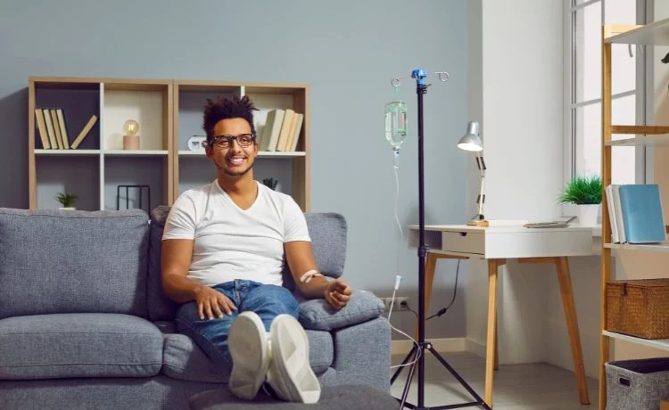 A male patient sitting on a couch receiving a ketamine infusion as a treatment for persistent depression near The Lakes, Las Vegas, NV.