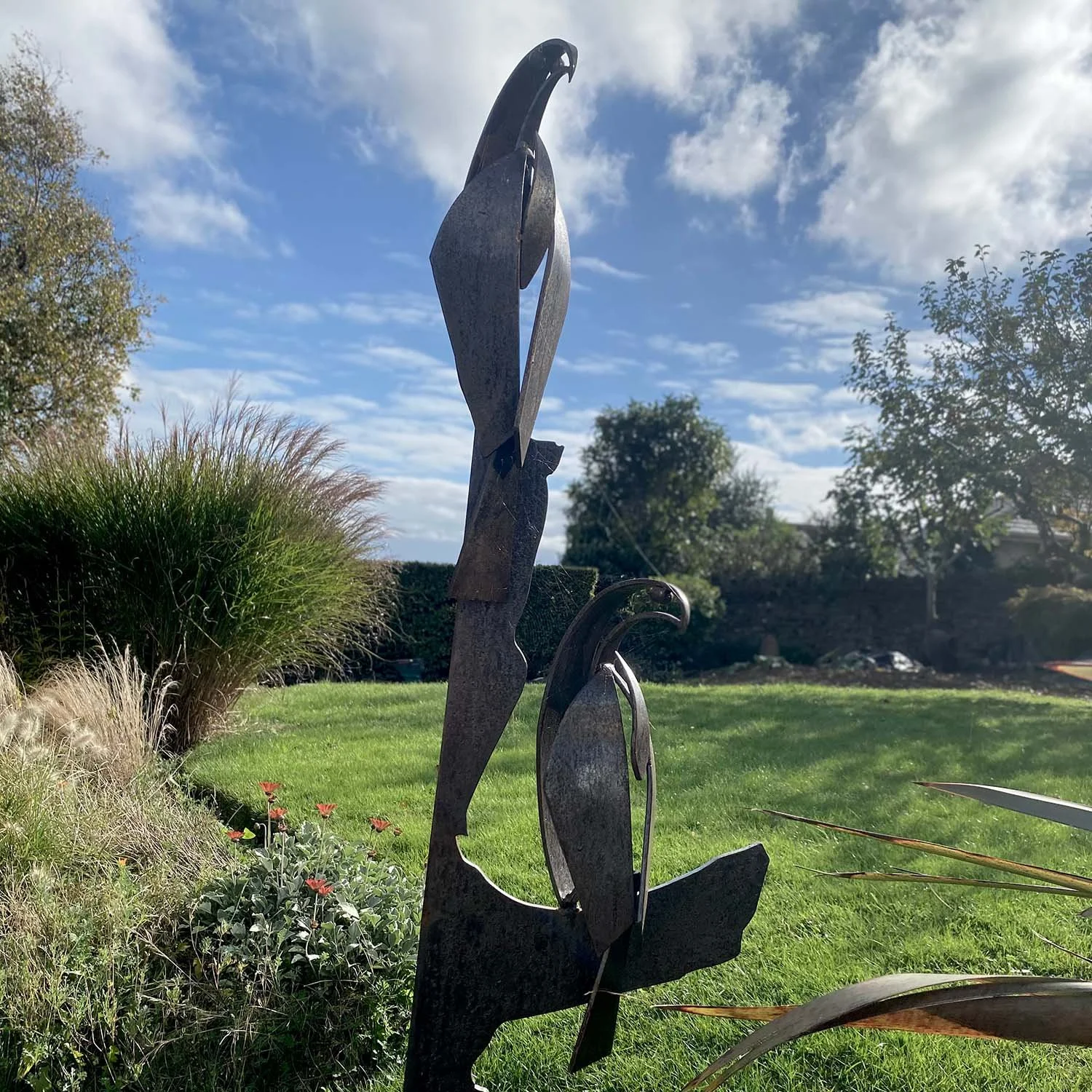outdoor metallic sculpture against lush green lawn and grassy borders