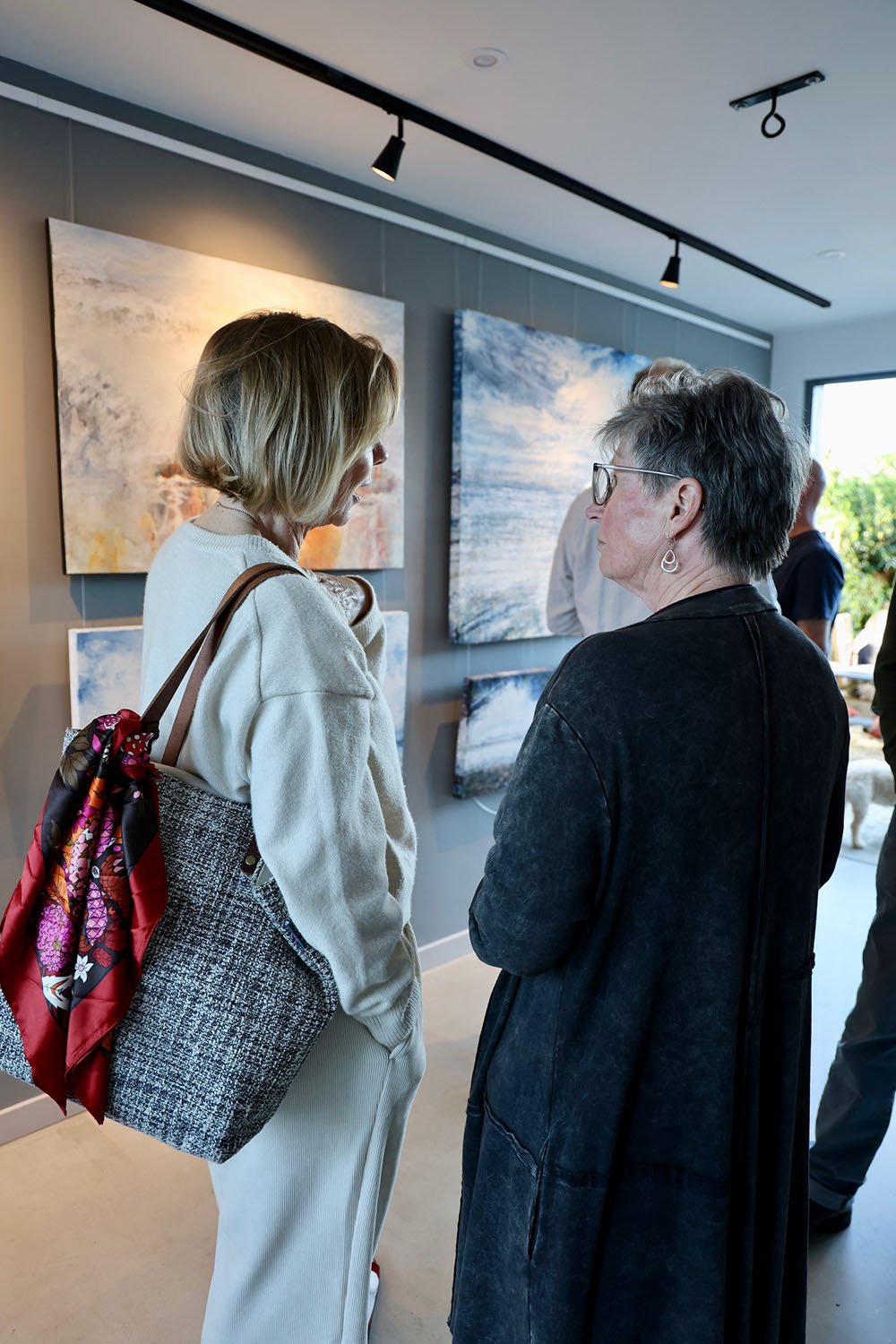 close upo of 2 ladies at private view event discussing the paintings on display