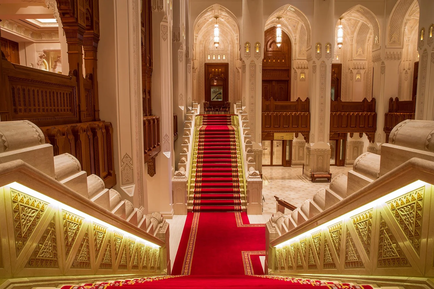 The Royal Oman Opera House lobby decorated with white Italian marble, dark wood from South-East Asia, red carpets, and luxury Arabian interior style