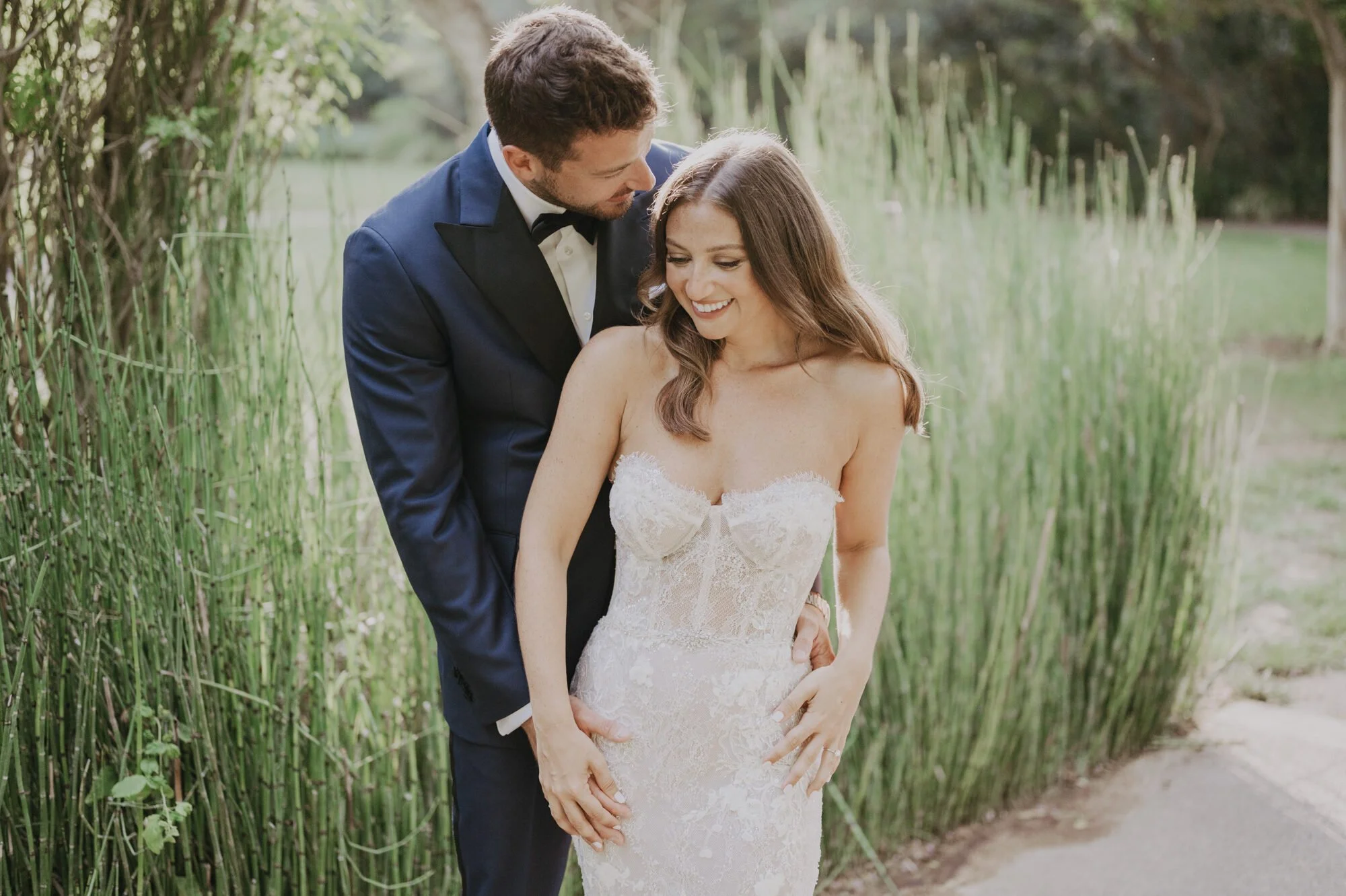 Groom whispering to his bride during an outdoor wedding portrait