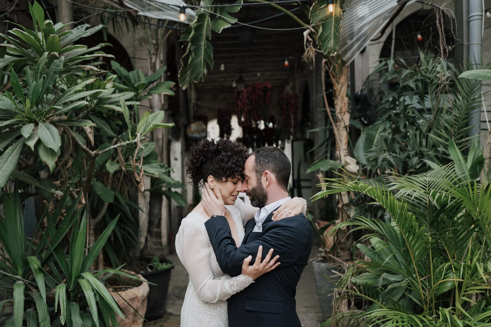 Couple sharing an intimate moment surrounded by tropical plants at their wedding venue