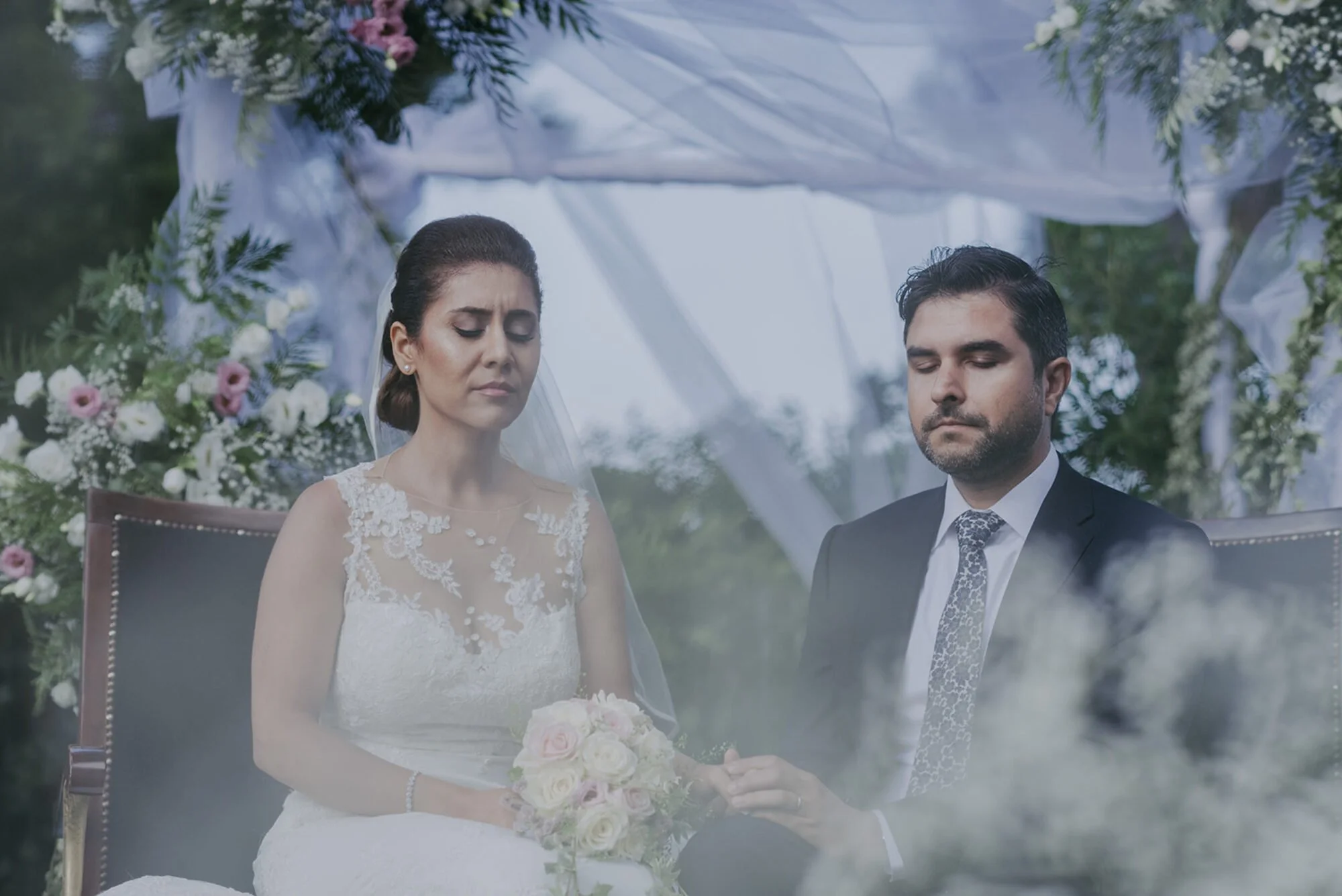 Bride and groom with eyes closed during an outdoor wedding ceremony