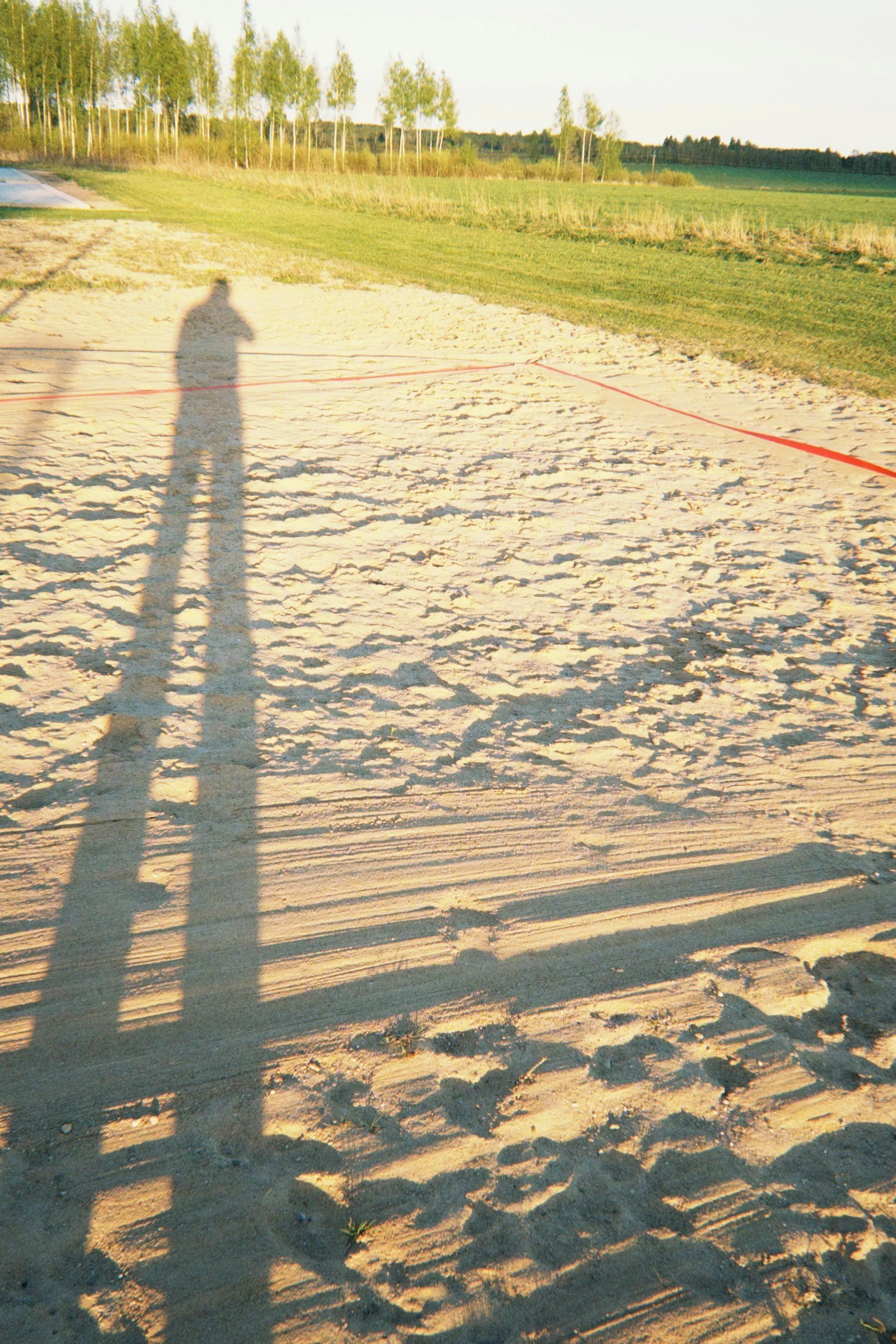 Long legged shadow cast from a human figure on a baseball field, representing the long shadow cast on an adulthood from having had to grown up too fast as a child