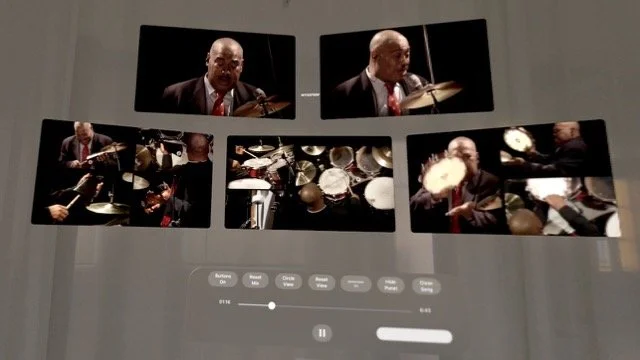 A digital screen displays multiple photos of a man playing the drums and a man playing the violin, with playback controls below.