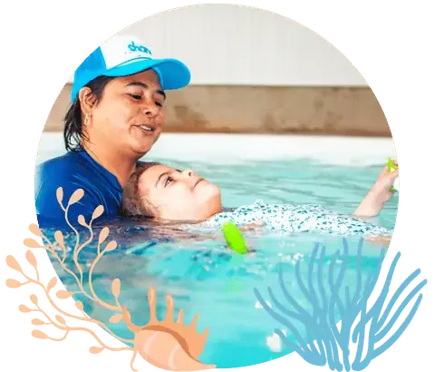 Swim instructor wearing dark blue swimwear teaching a child to float inside a poolSwim instructor wearing dark blue swimwear teaching a child to float inside a pool