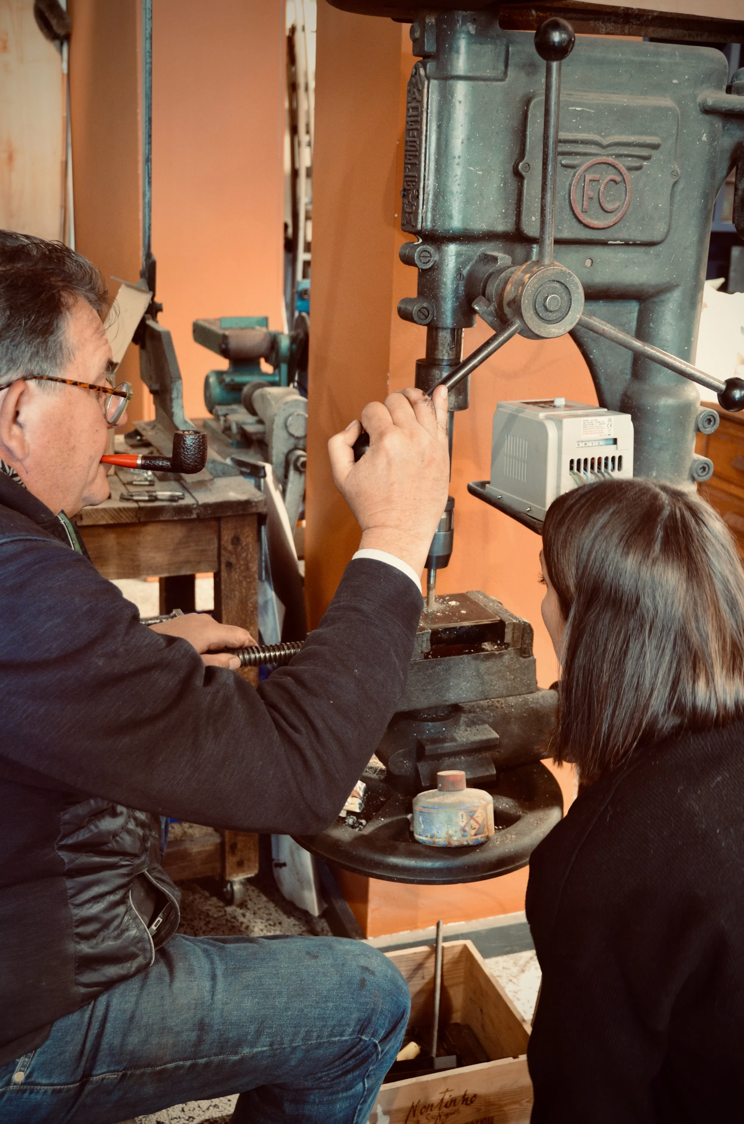 Un homme et une jeune fille utilisent une machine-outil dans un atelier de métallurgie fine.