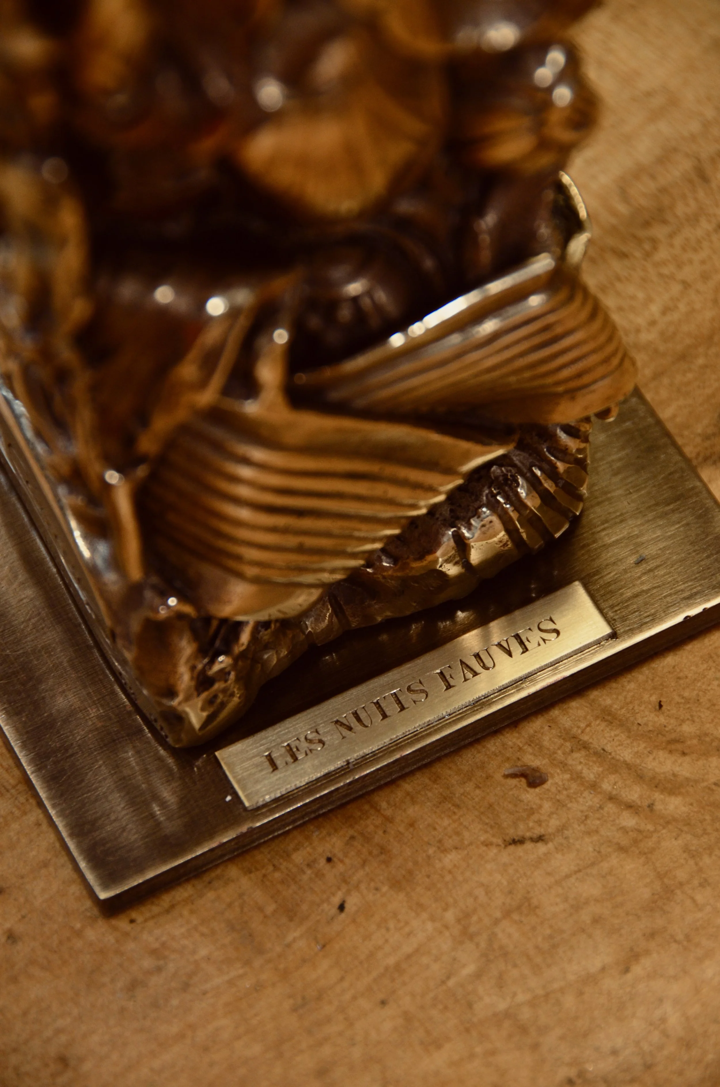 Une sculpture en bois représentant une tête d'animal, probablement un lion, posée sur une plaque avec l'inscription 'LES NUIT SLIM LES NUIT SLIM'.