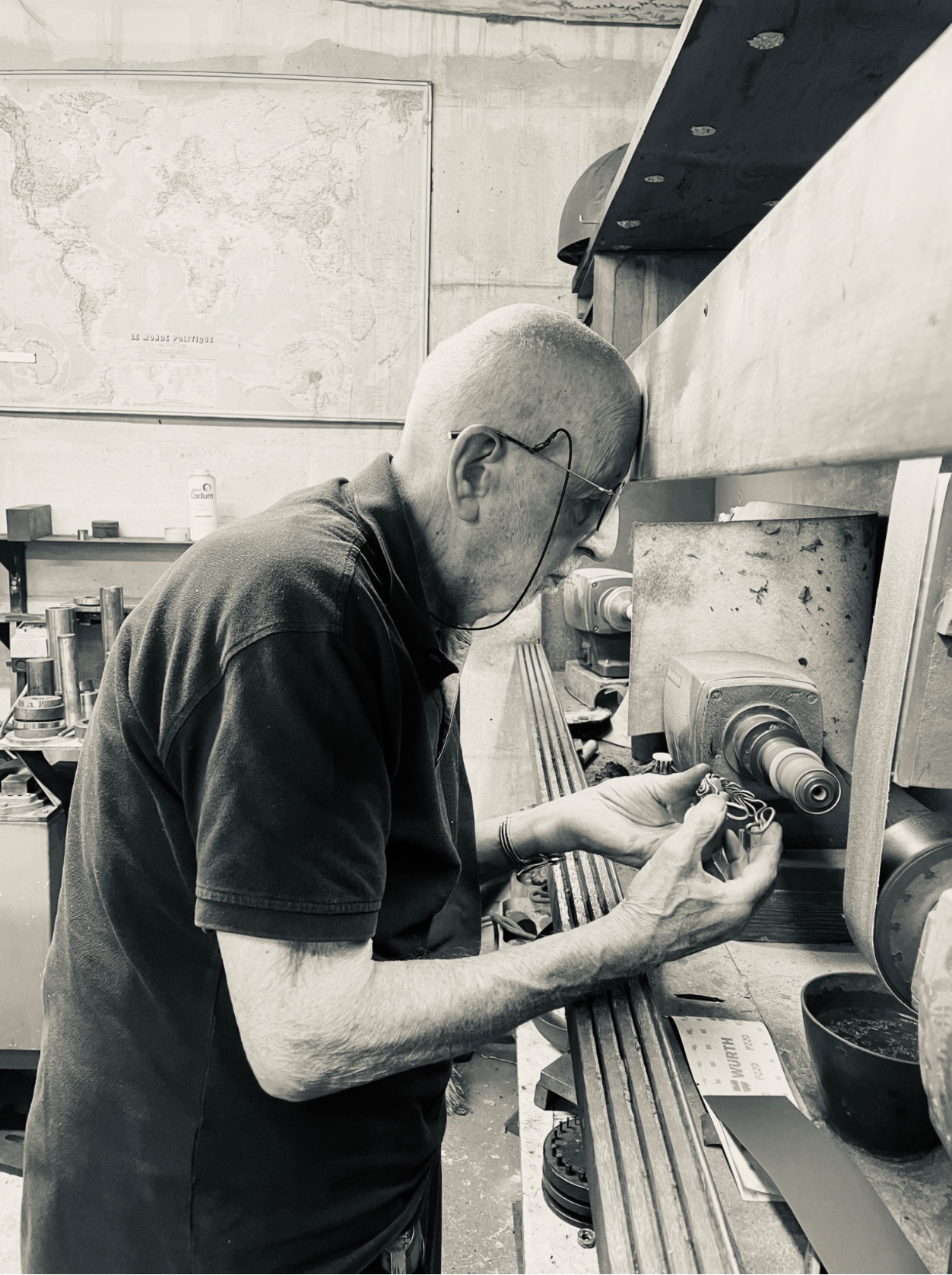 Jacques Moniquet travaille avec une machine dans un atelier, portant des lunettes de sécurité et un t-shirt noir.