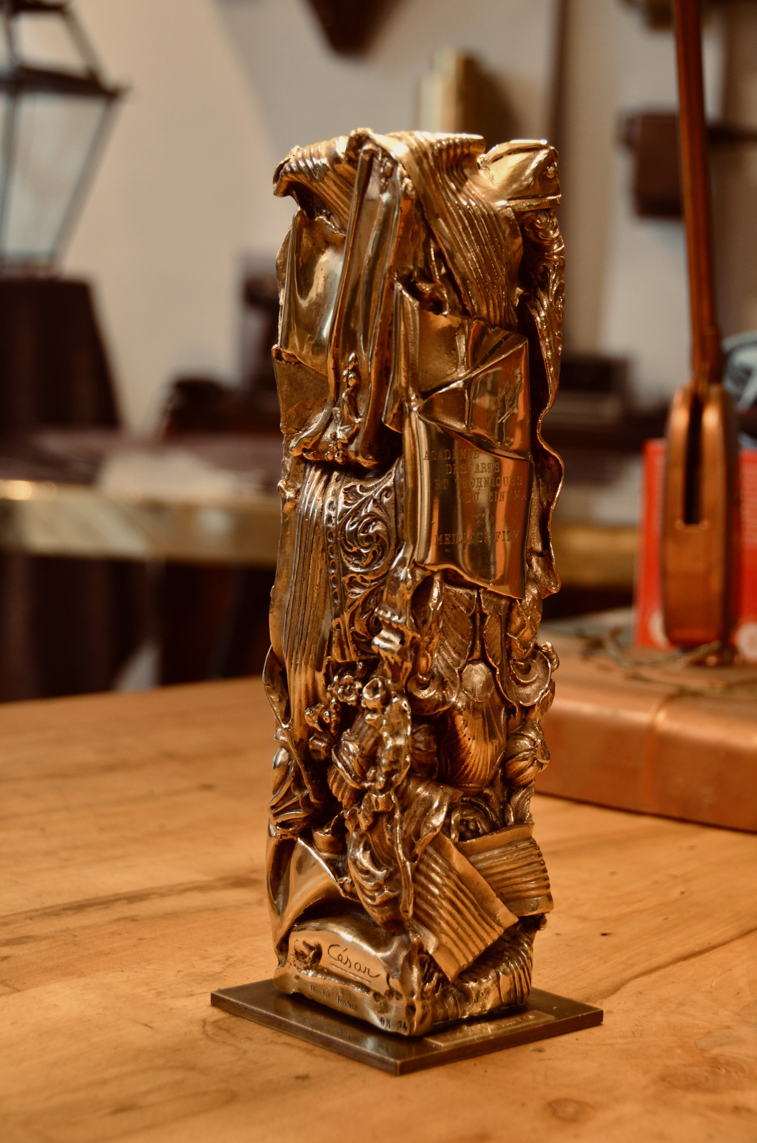 Une sculpture en bronze représentant des motifs floraux et artistiques, posée sur un socle sur mesure