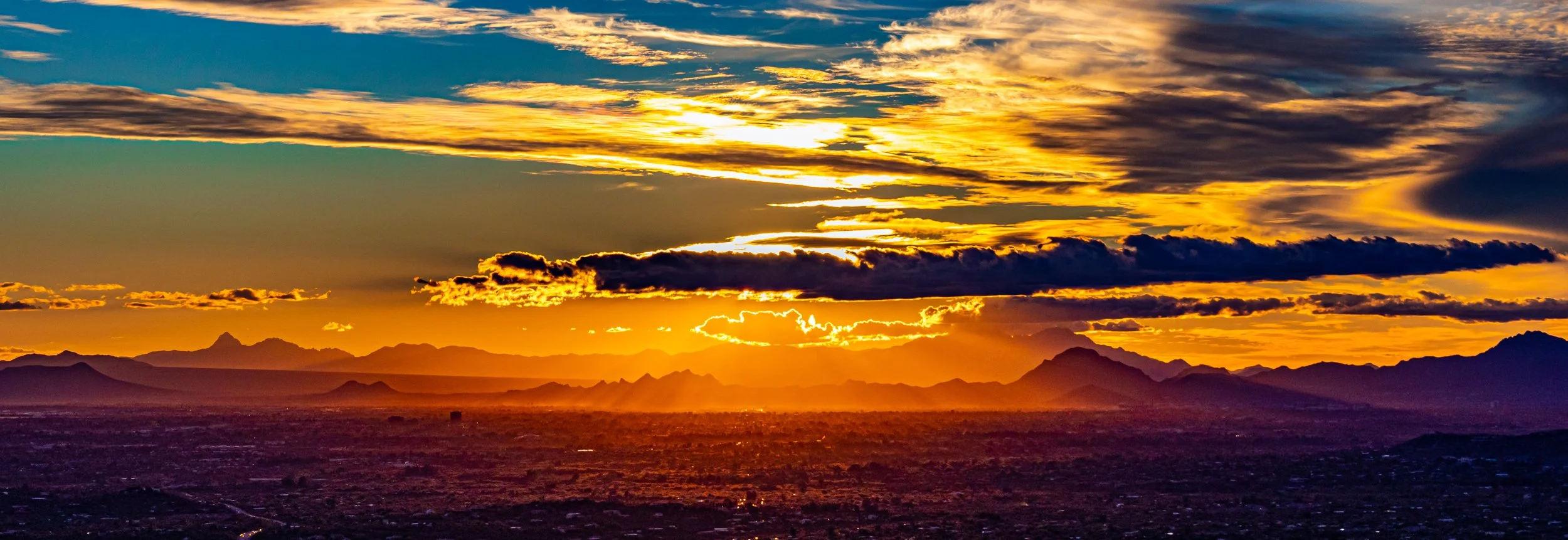 Dramatic sunset over Tucson, Arizona with glowing desert landscape and mountain silhouettes, showcasing the beauty and lifestyle of Southern Arizona.