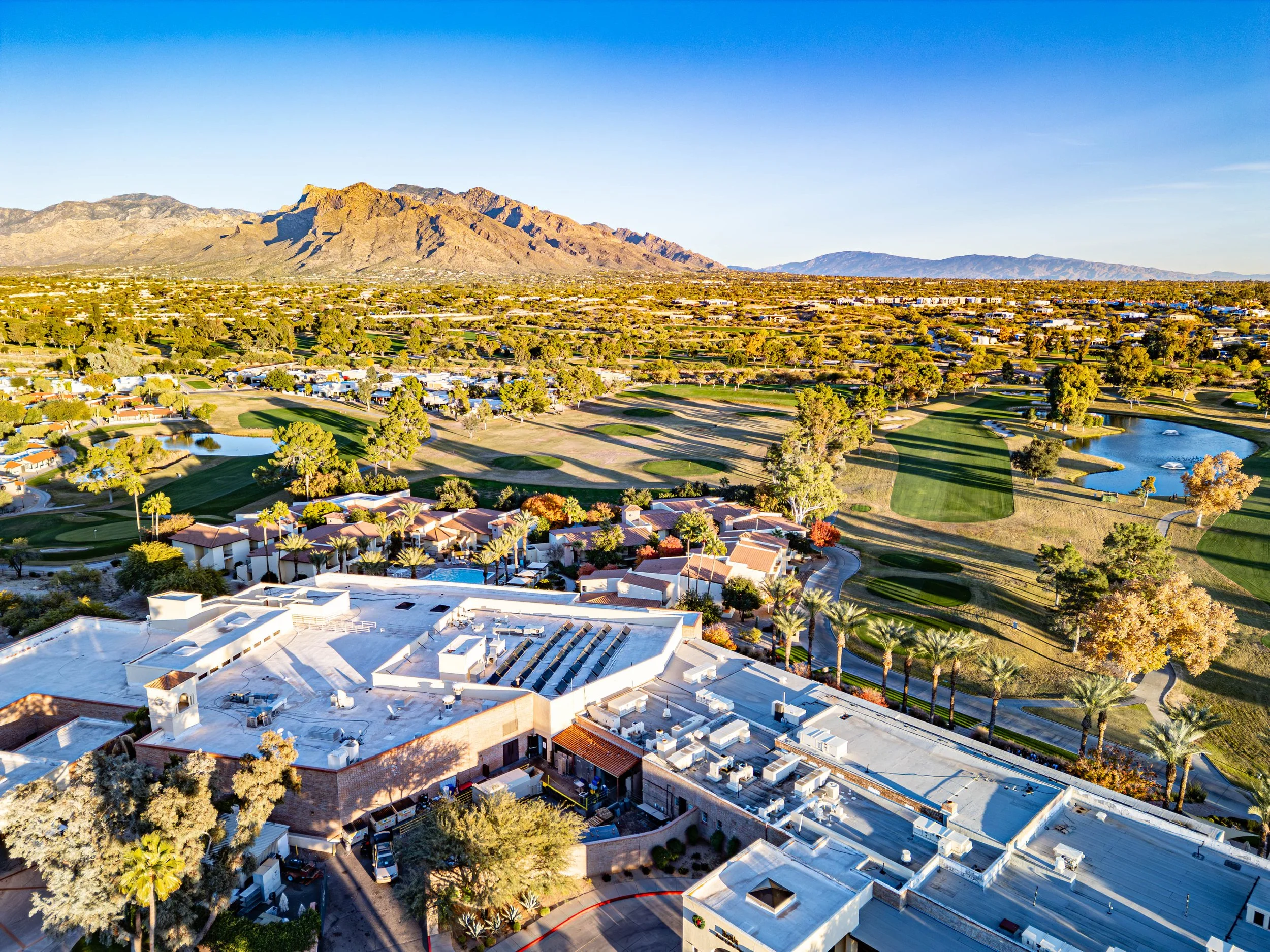 Aerial view of Casas Adobes neighborhood in Tucson, Arizona featuring golf courses, desert homes, and the Catalina Mountains in the background.