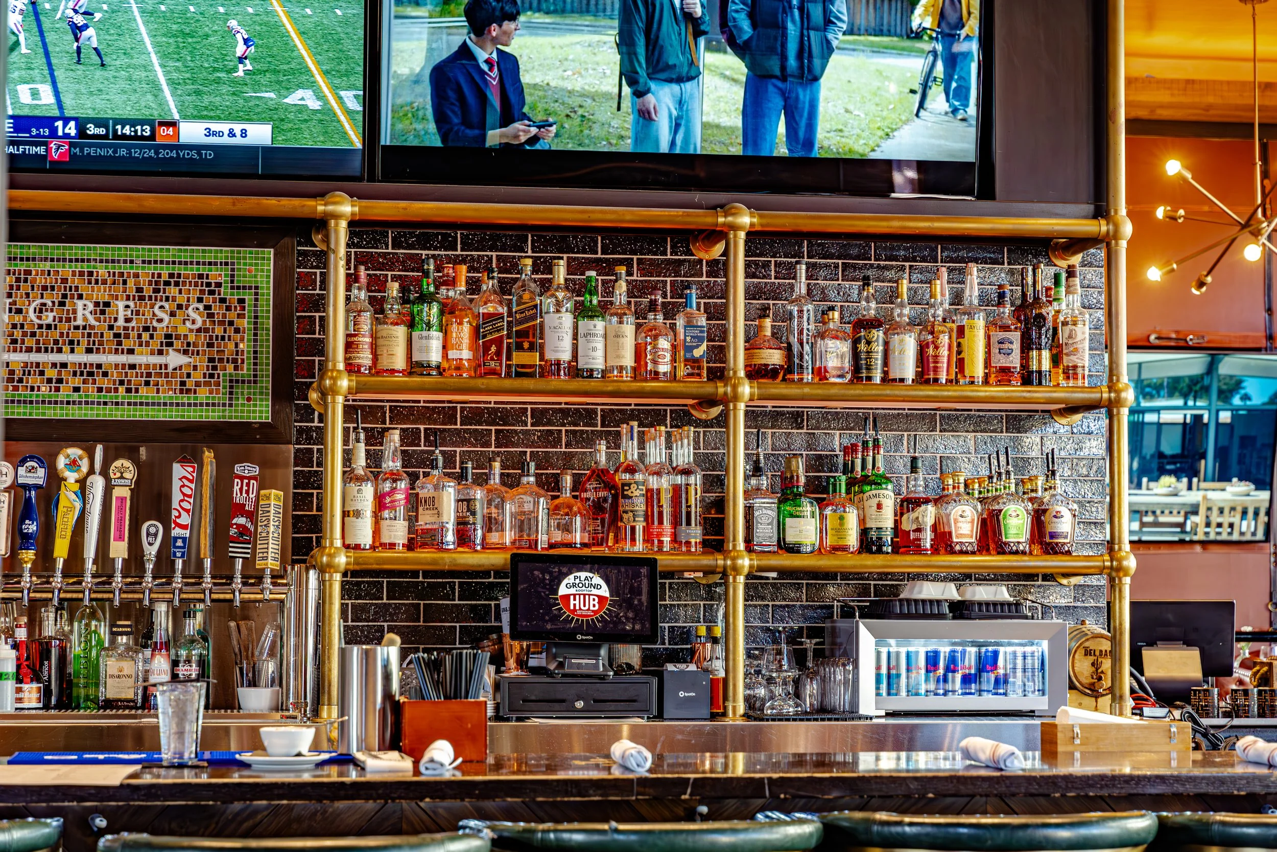 Bar area inside The HUB Restaurant & Ice Creamery in Downtown Tucson featuring craft beer taps, liquor shelves, large televisions, and a modern industrial design.