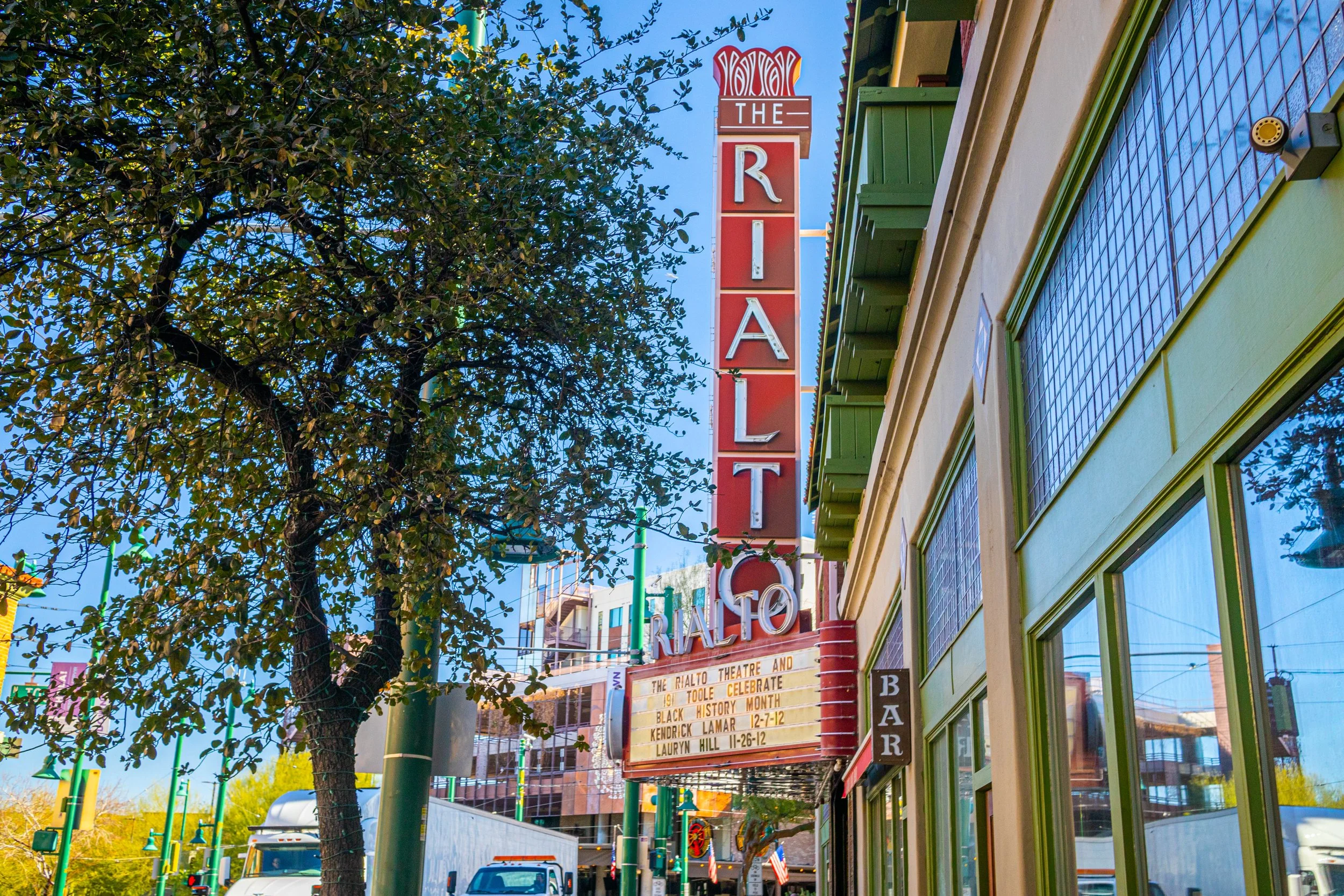 Historic Rialto Theatre marquee on Congress Street in Downtown Tucson, Arizona, surrounded by historic buildings, trees, and the city's vibrant entertainment district.