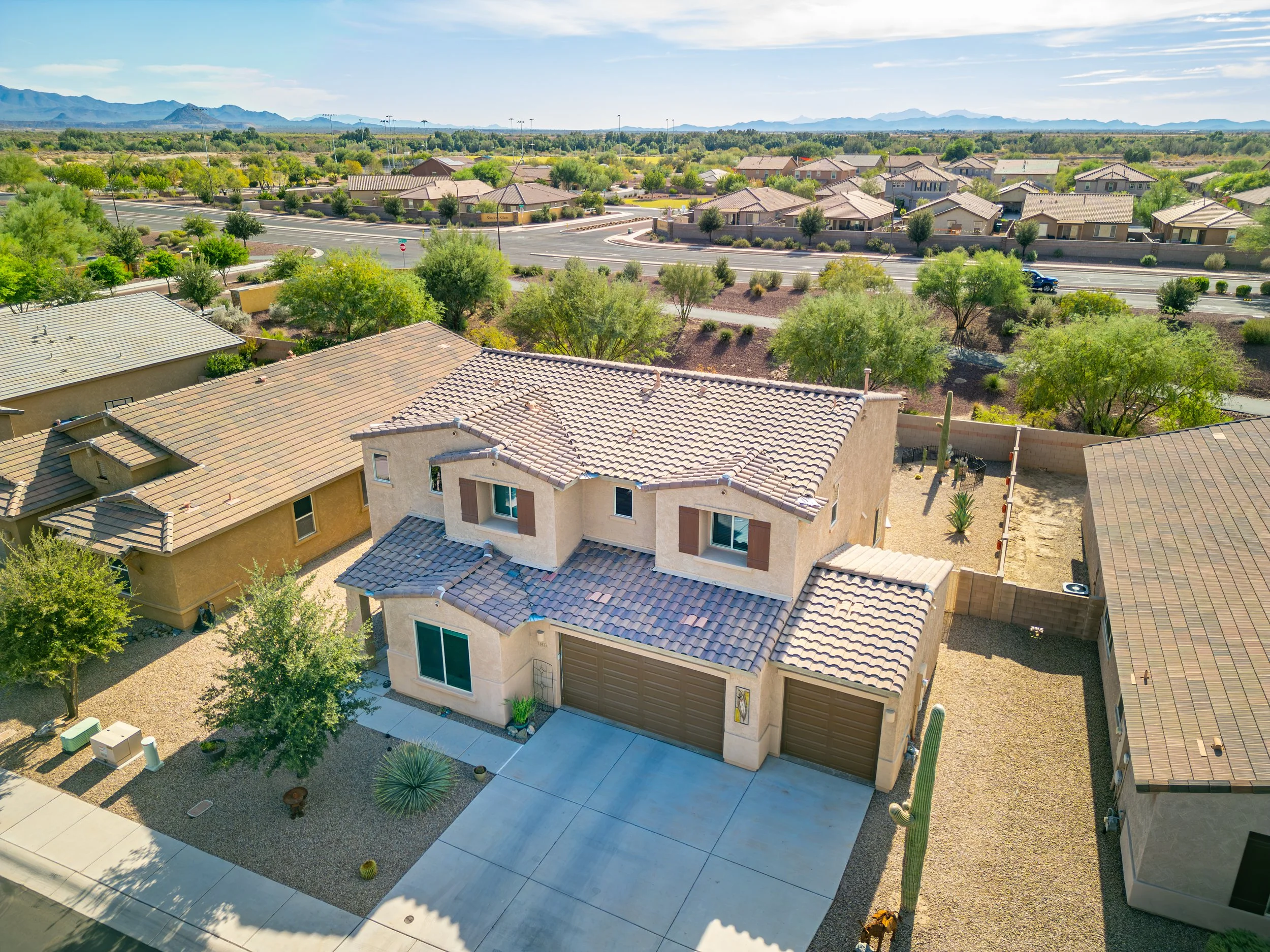 Aerial drone image of a two-story home in the Gladden Farms neighborhood of Marana, Arizona, surrounded by desert landscaping and suburban homes with mountain views in the distance.