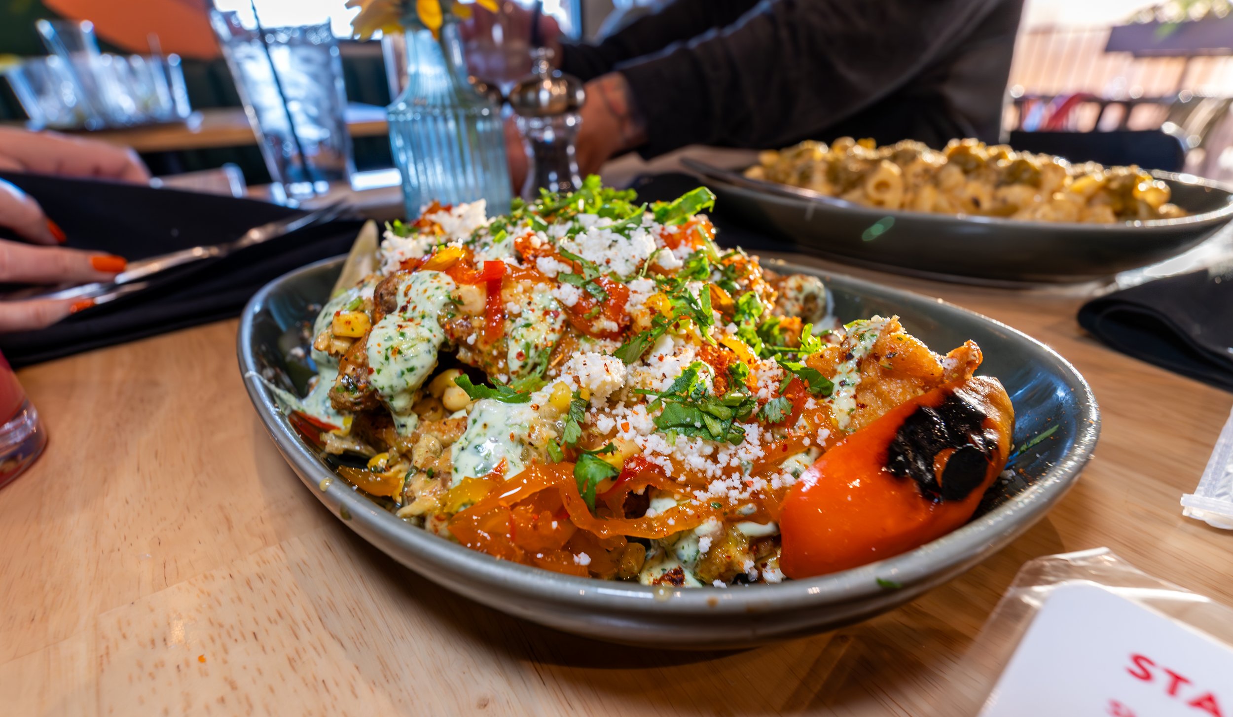 Loaded nachos topped with corn, peppers, crumbled cheese, cilantro and creamy sauce at Redbird Scratch Kitchen in Tucson.