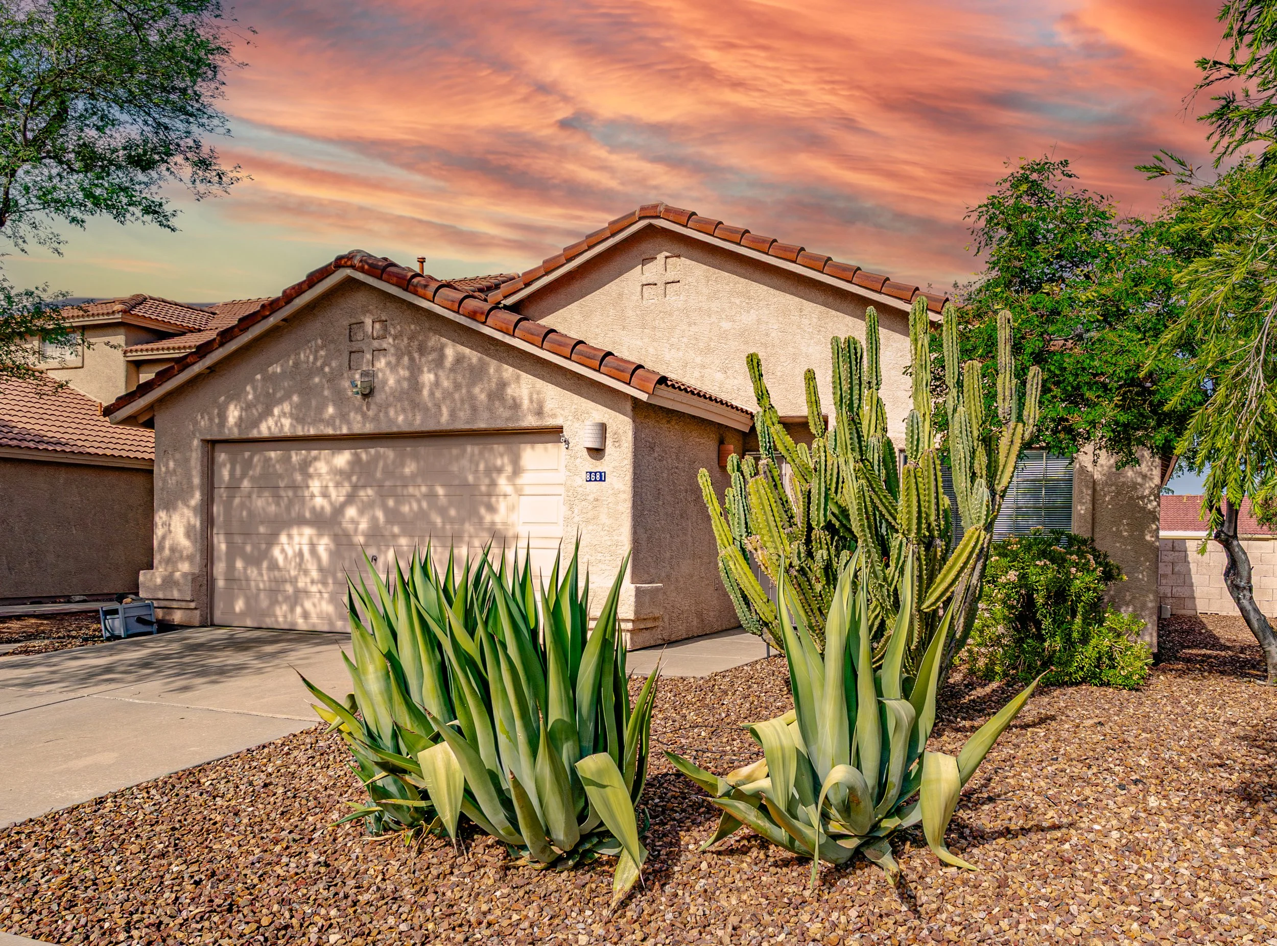 Southwestern-style home on Tucson’s west side featuring desert landscaping, agave plants, cacti, and a colorful Arizona sunset.