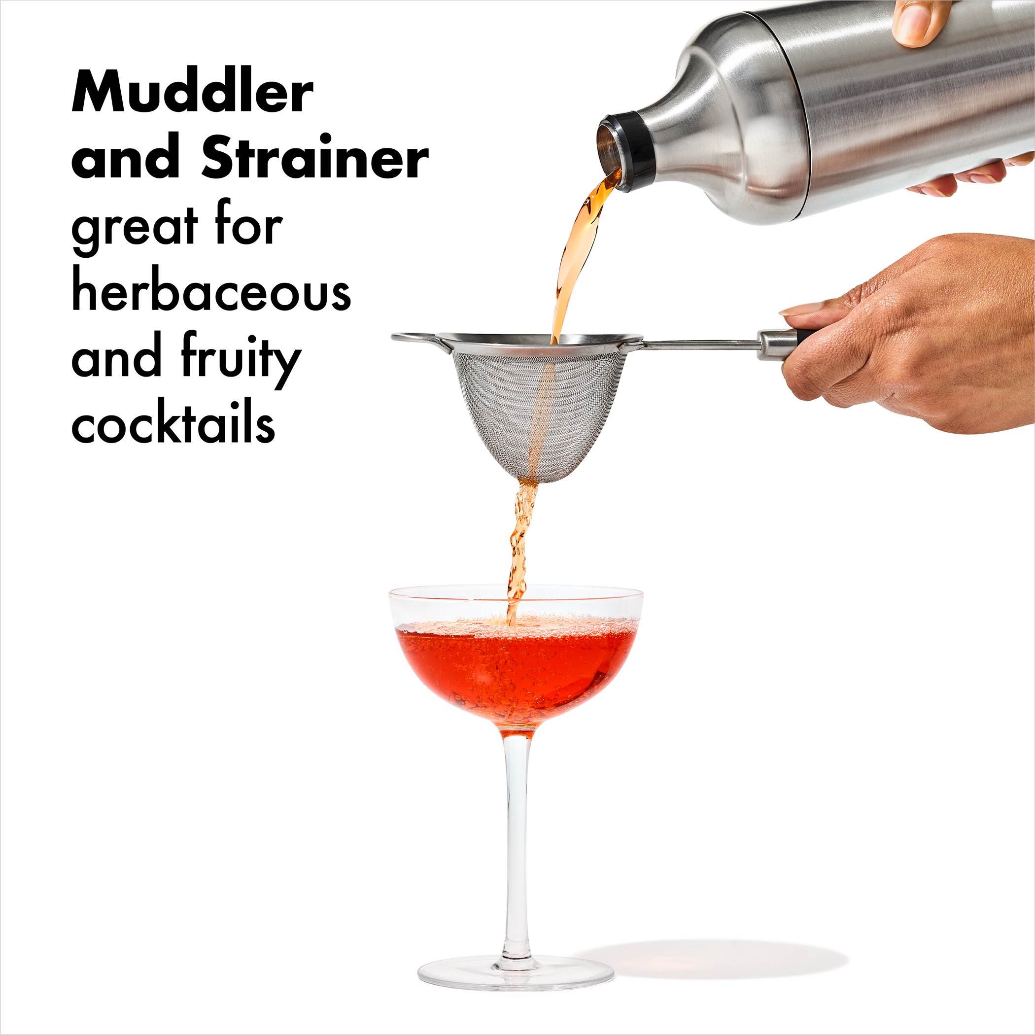 Person pouring cocktail through strainer into coupe glass – "OXO cocktail strainer in action for herbaceous drinks