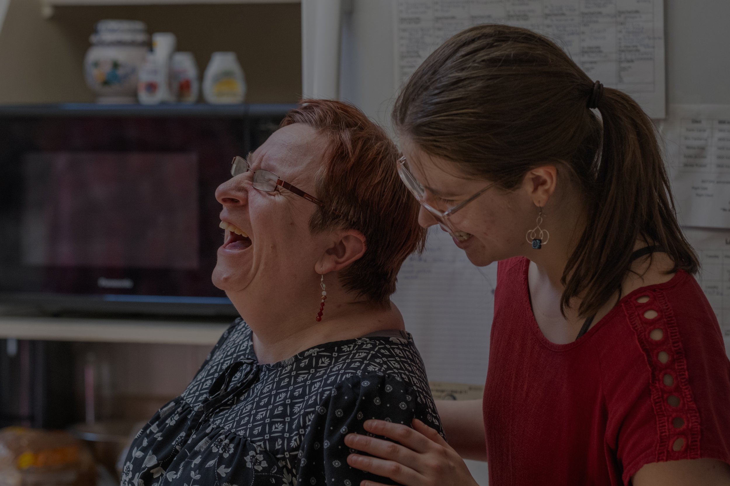 person with diverse abilities and care taker laughing