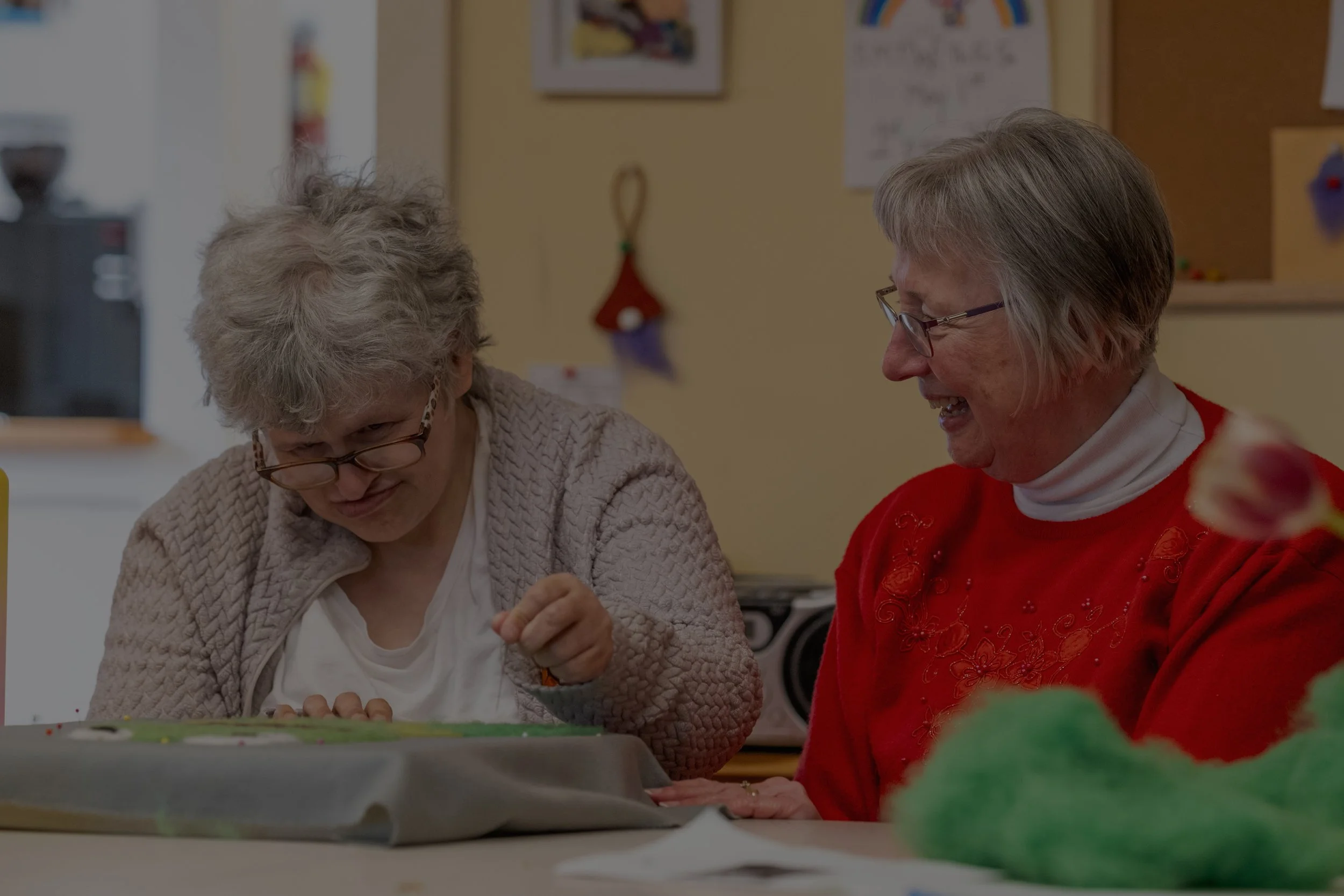person with diverse abilities with care taker working on crafts together