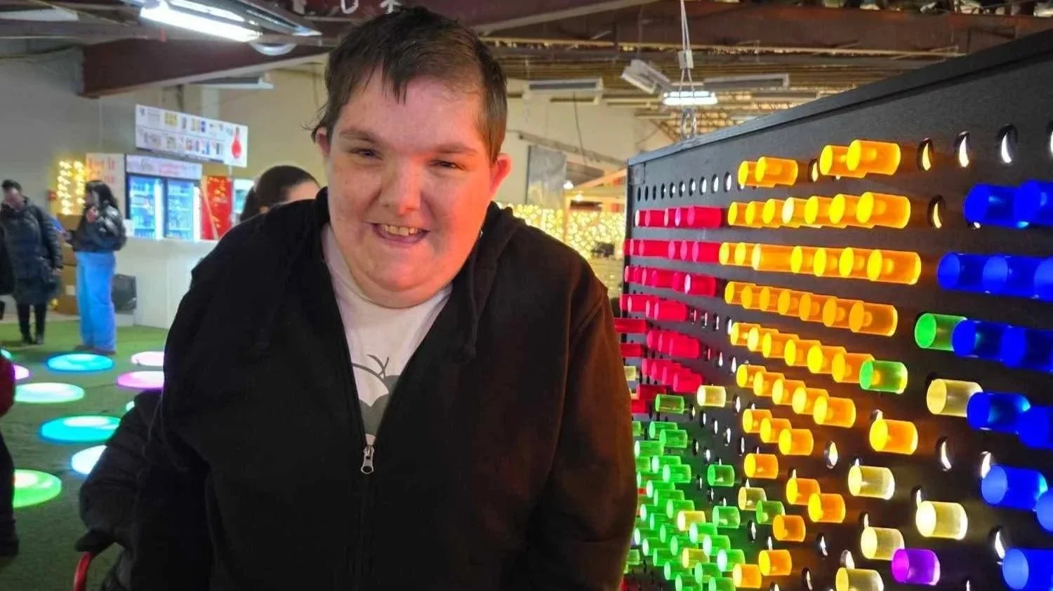 A woman smiling beside a giant Lite-Brite