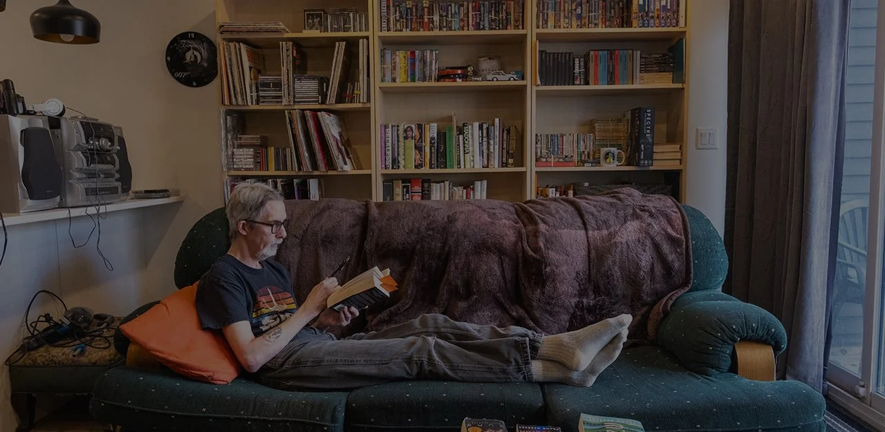 Man lounging on couch reading a book.