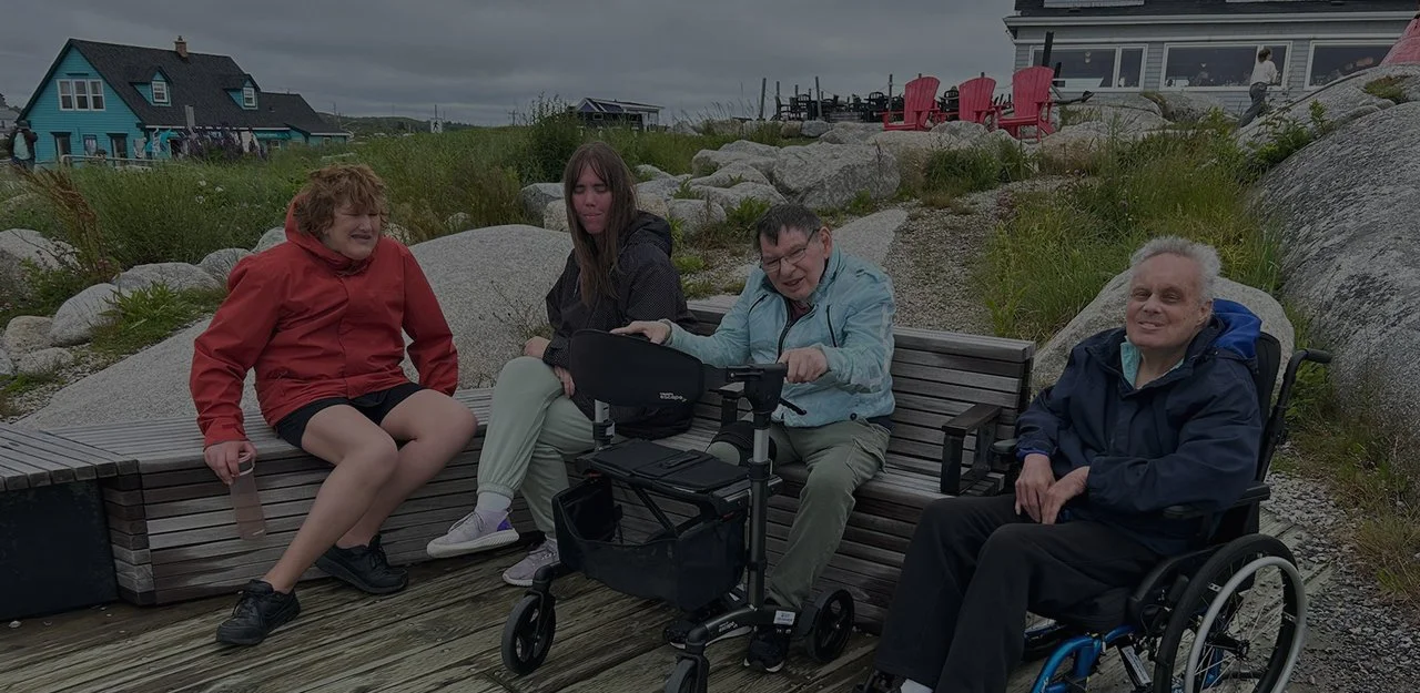 Four people sitting on rocks at Peggy's Cove, NS.
