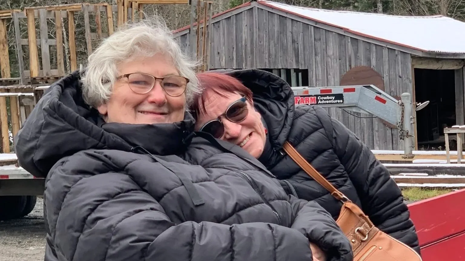 Two women in black jackets sitting beside each other