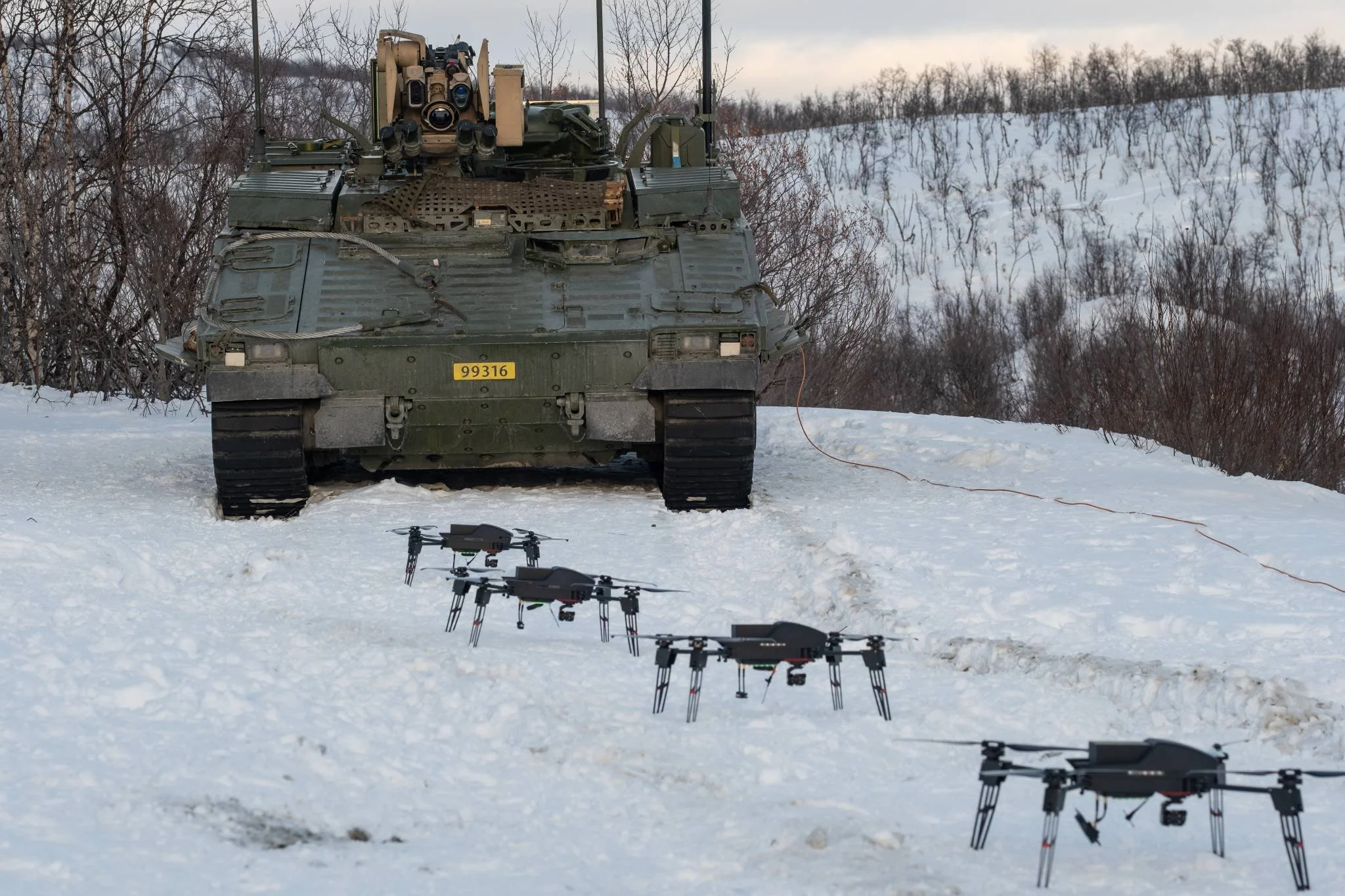Military tank in snow with swarm drones