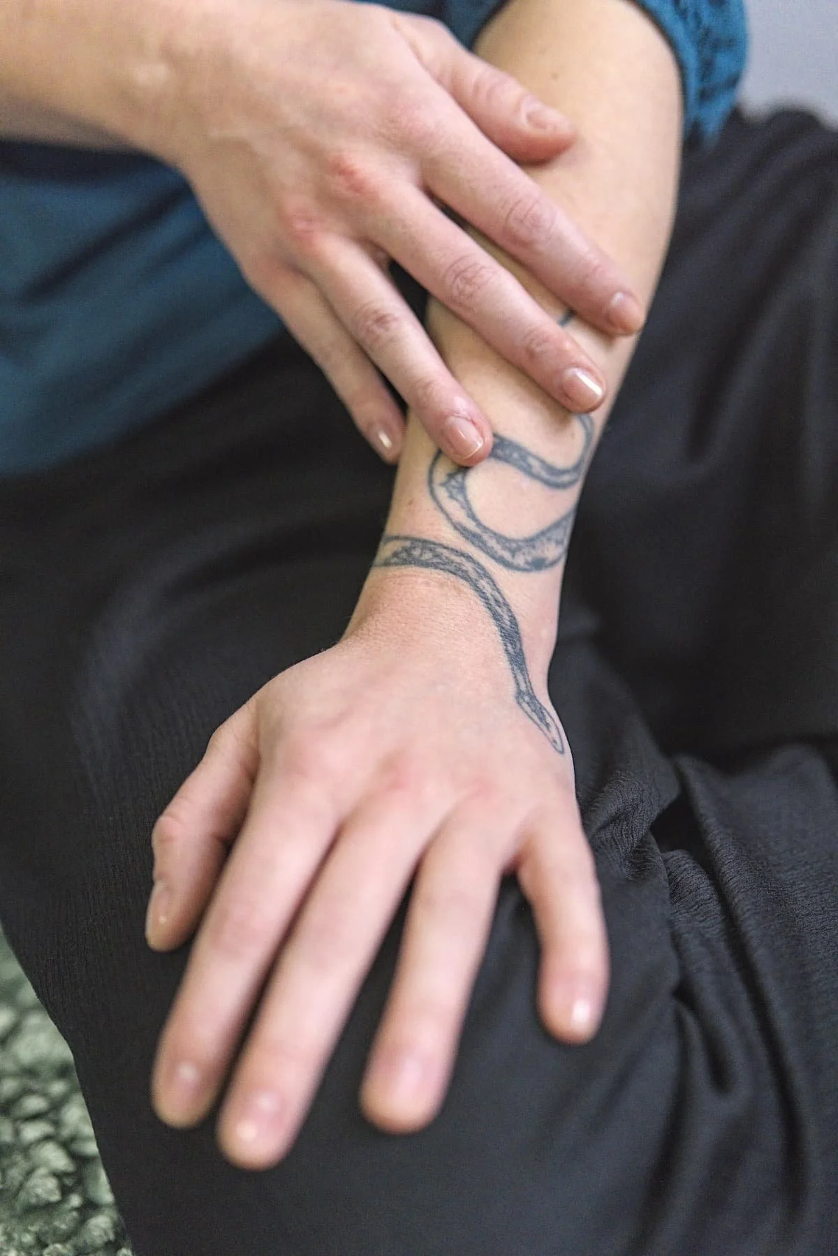 Berührungscoach Eva Hanson berührt ihren Arm mit dem Schlangentattoo