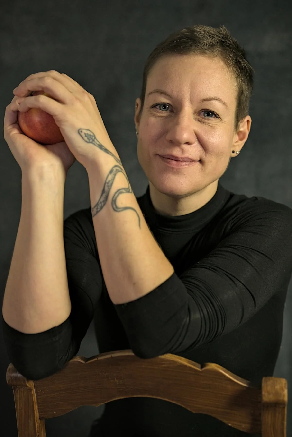 Frauenmasseurin Eva Hanson vor dunklem Hintergrund mit Apfel in den Händen