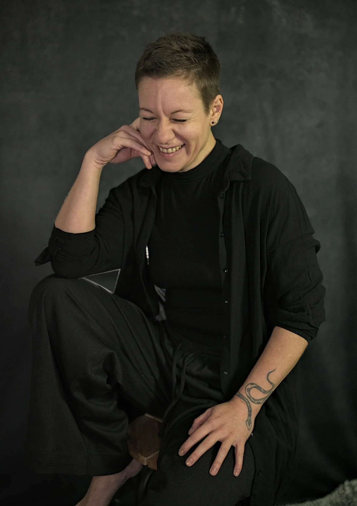 Tantra-Masseurin Eva Hanson barfuß auf Hocker, lacht