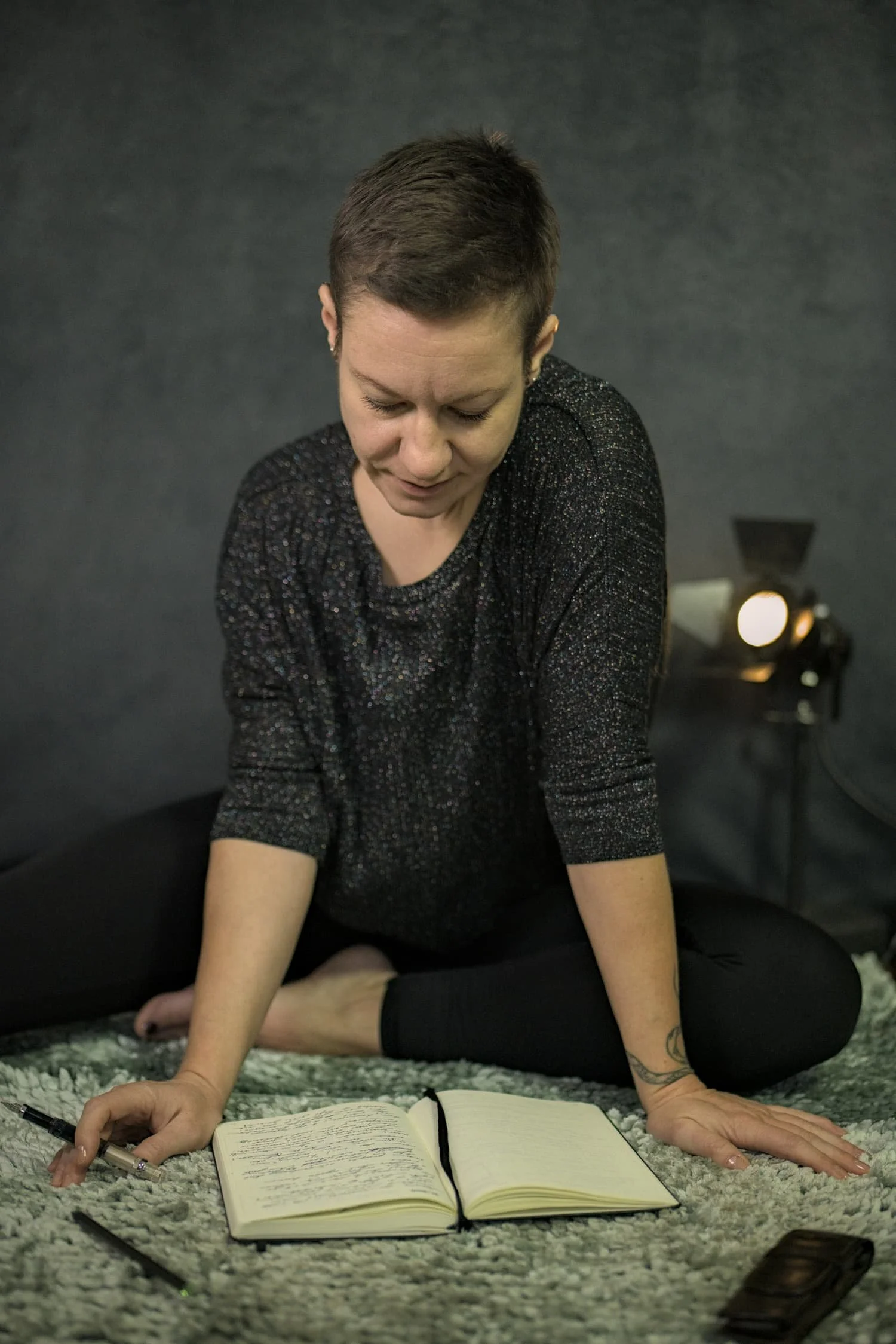 Eva Hanson mit Notizbuch auf dem Boden sitzend