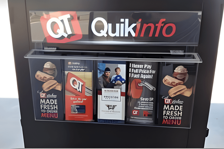A QuikTrip newspaper vending machine with advertisements, a red paper money slot, and a mechanical handle for dispensing newspapers.