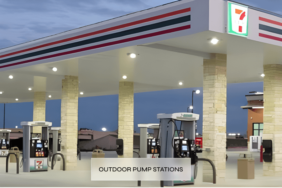 Seven outdoor gas pump stations at a 7-Eleven convenience store during evening with illuminated pumps and store signage, brick columns, and a trash bin.