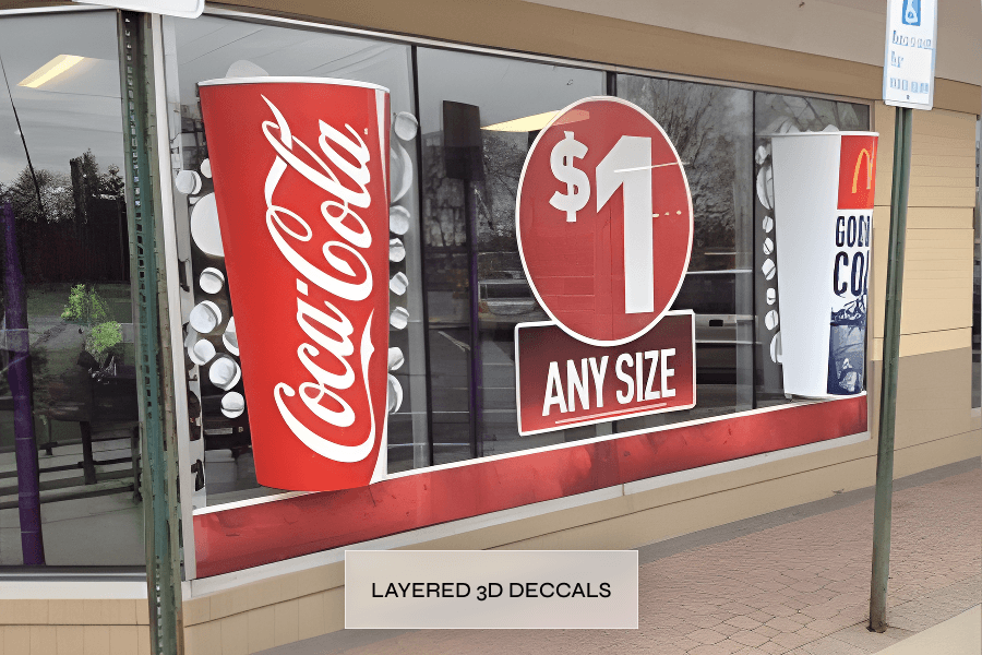 Store window advertising Coca-Cola cups for $1 any size, with the Coca-Cola logo on the left and another beverage cup on the right, and a circular sign in the center showing "$1".