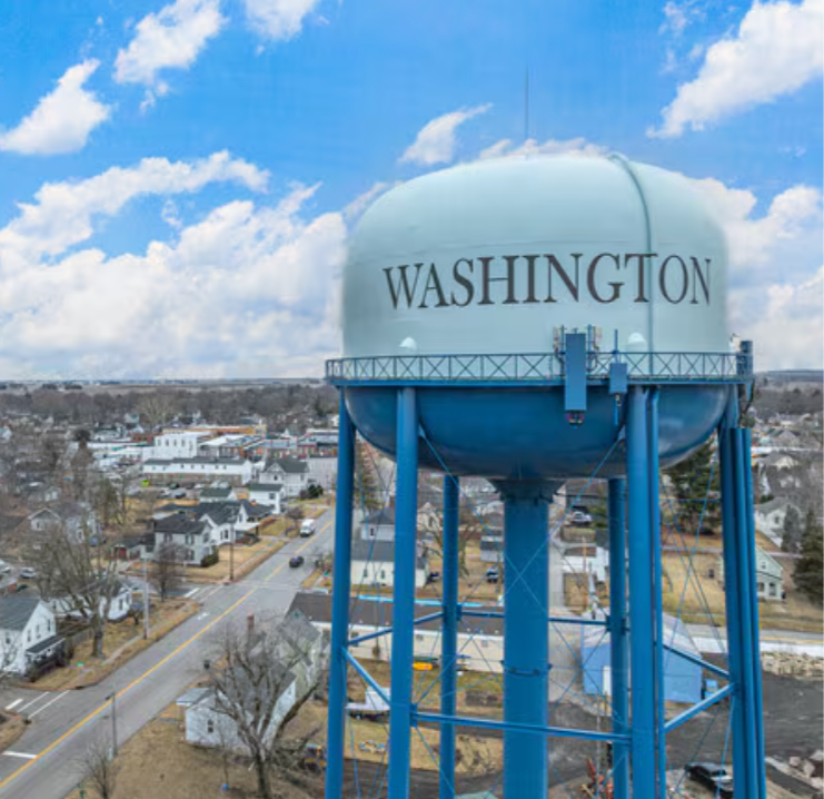 Water tower with Washington written on it, overlooking a residential neighborhood.