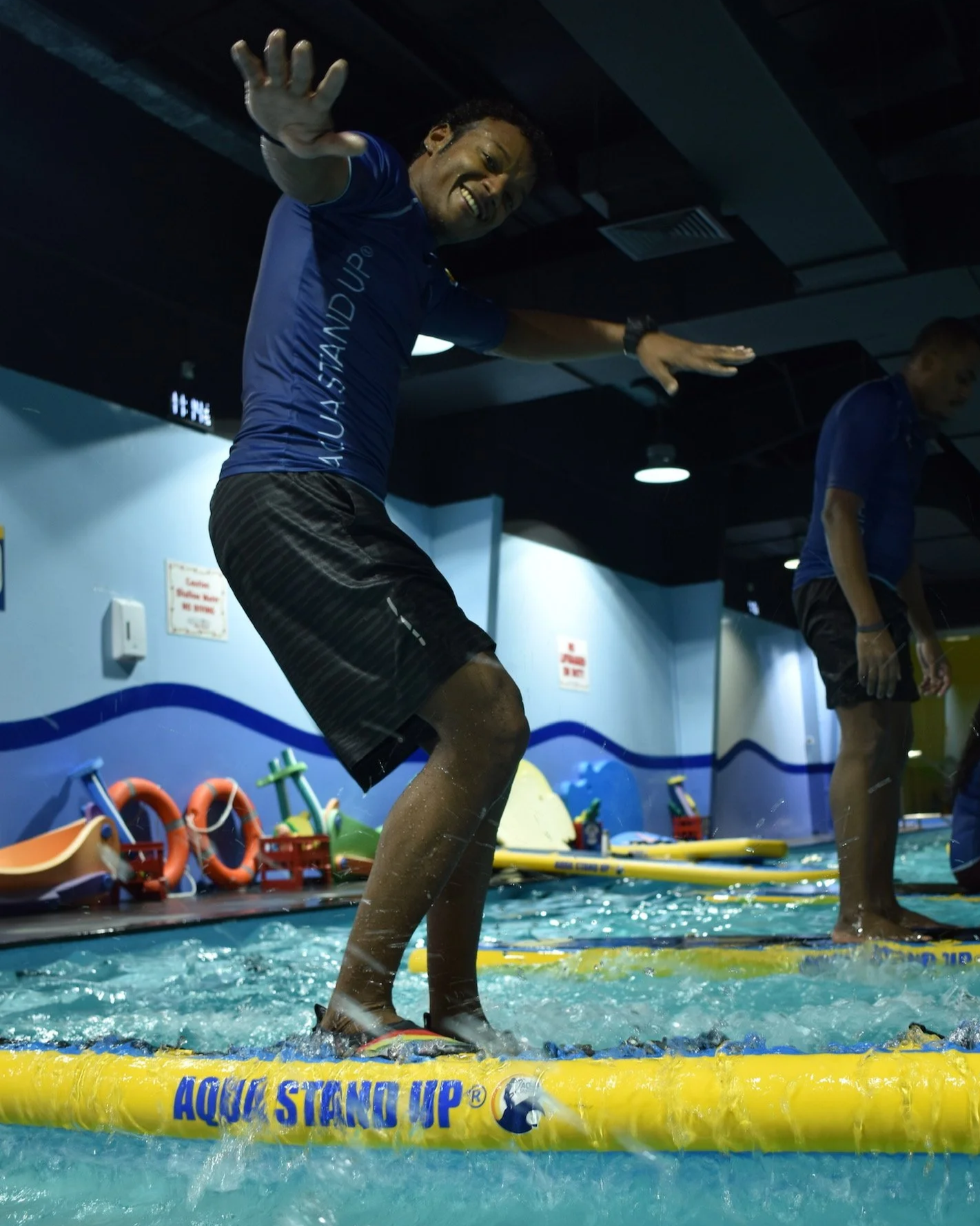 AQUA STAND UP® Instructor standing up on an aqua stand up paddle board during a workout in a swimming pool