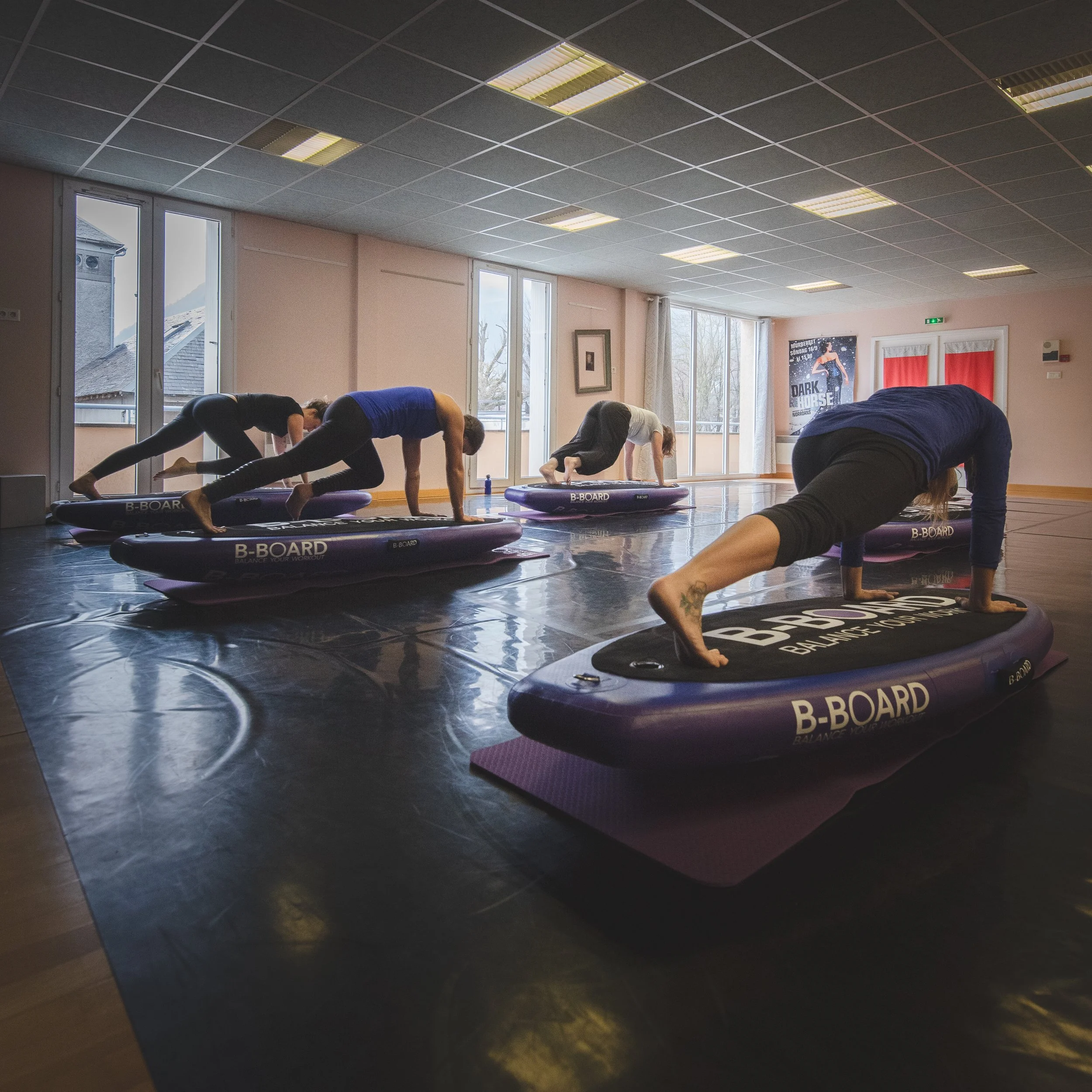 group of participants in a fitness room, performing mountain climbers on balance boards during a B-BOARD® yoga class