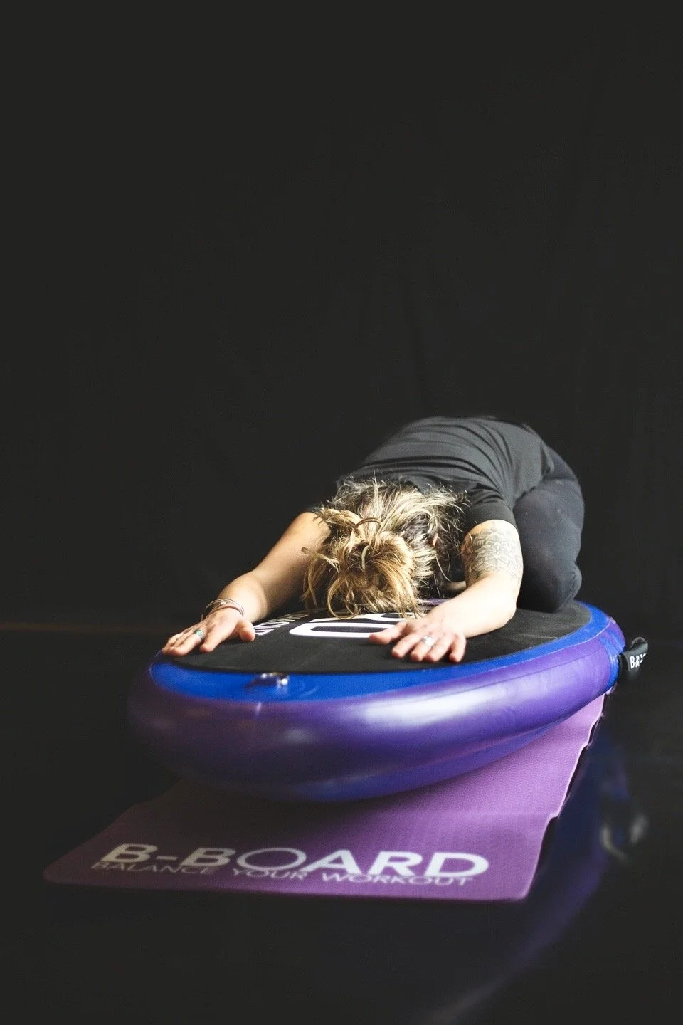 woman performing a child pose on a balance board called B-BOARD®