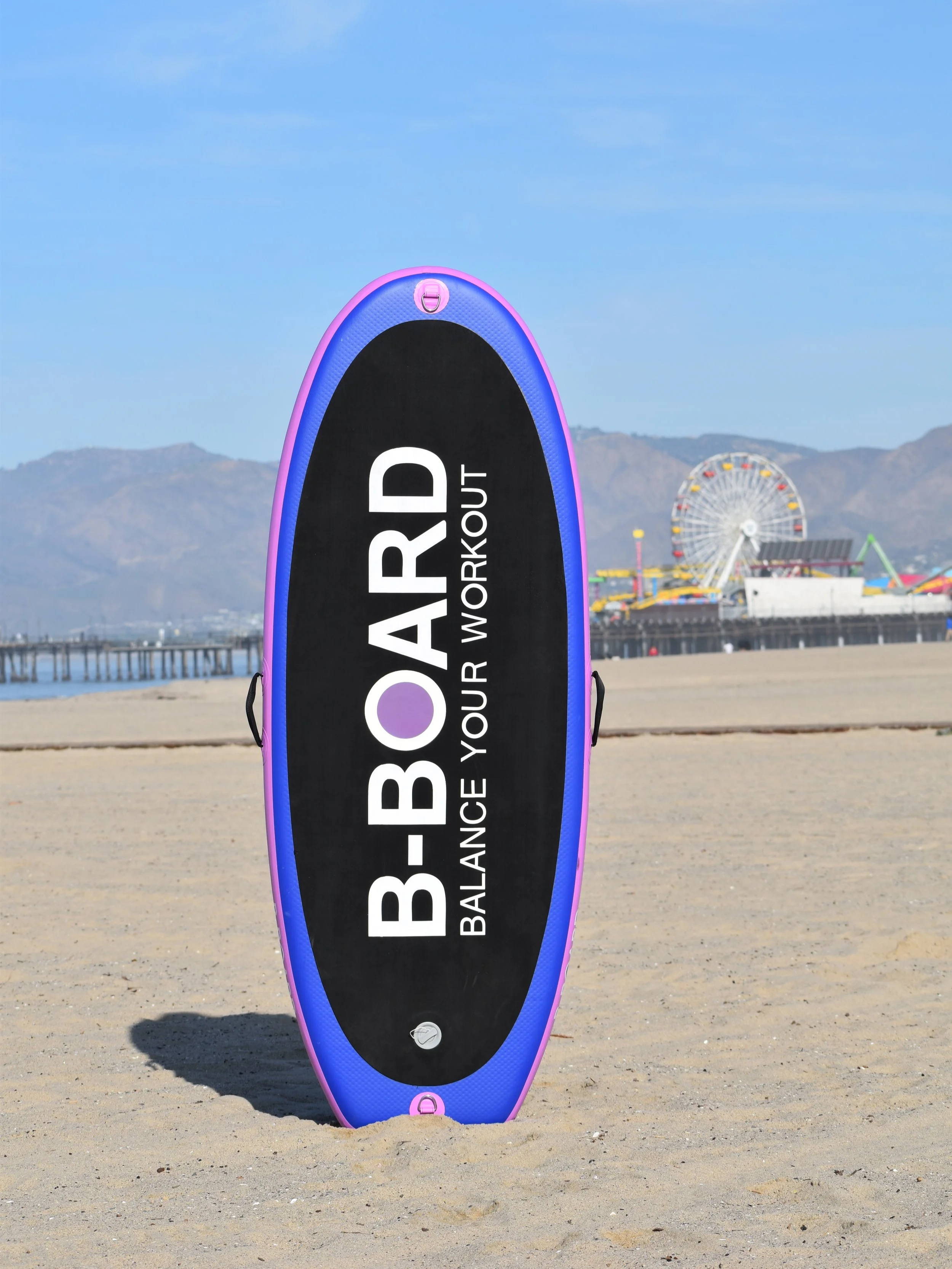 bboard balance board standing up on the sand in a beach setting with the santa monica pier in the background