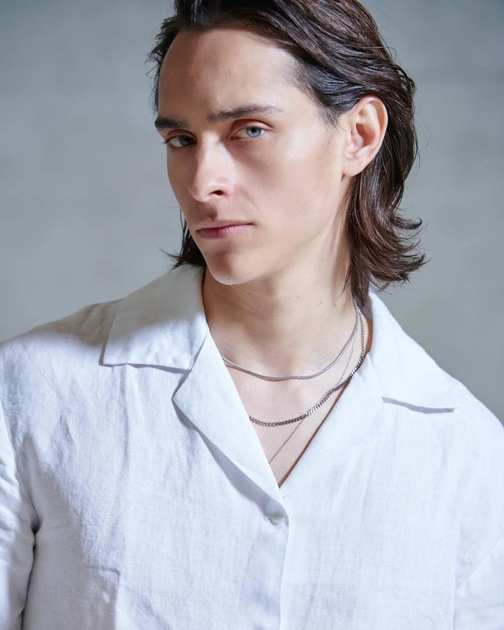young model vegan oji blue eyes, with a white shirt and grey background
